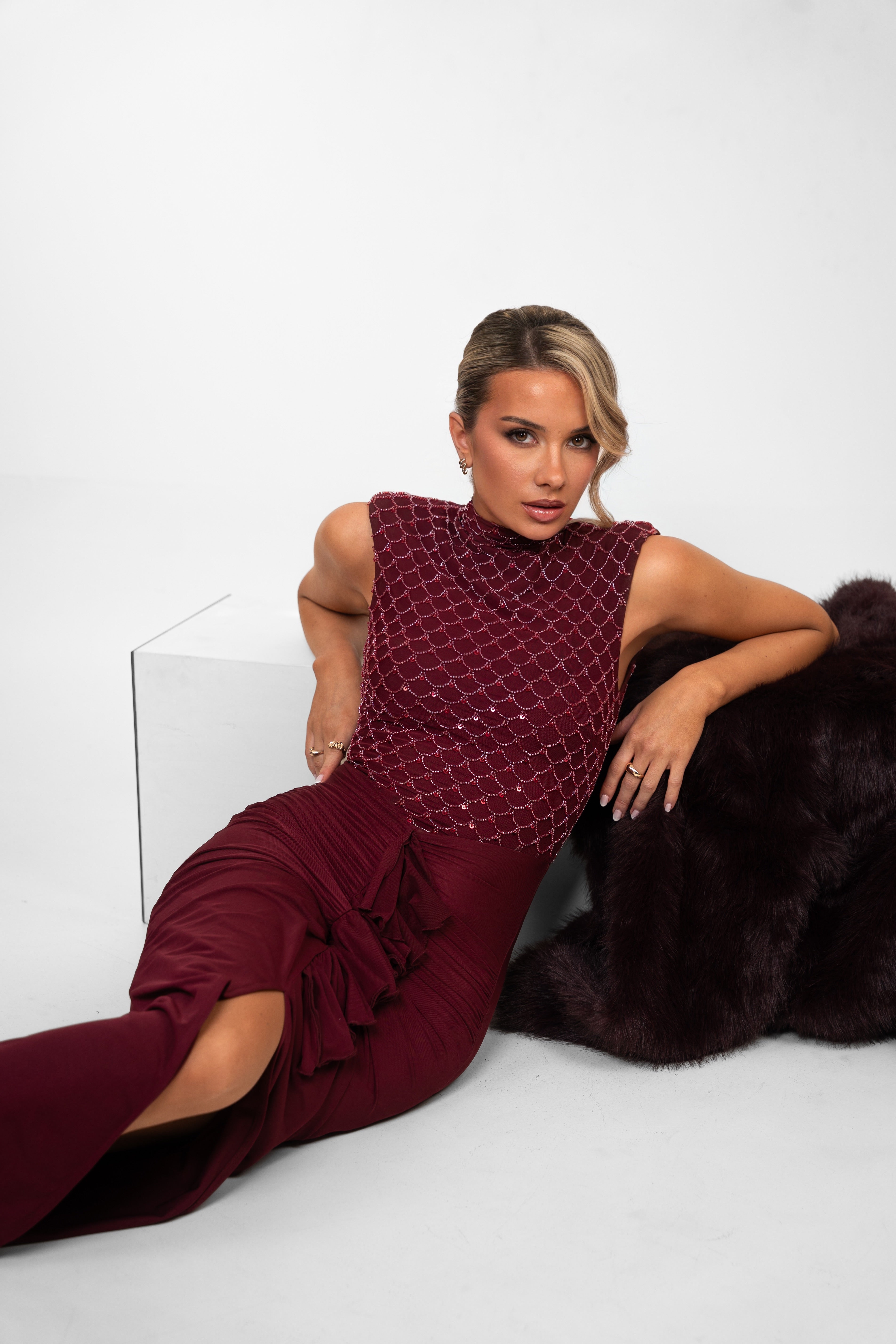 Long maroon gown with sequined top and front ruffle that gathers at the waist