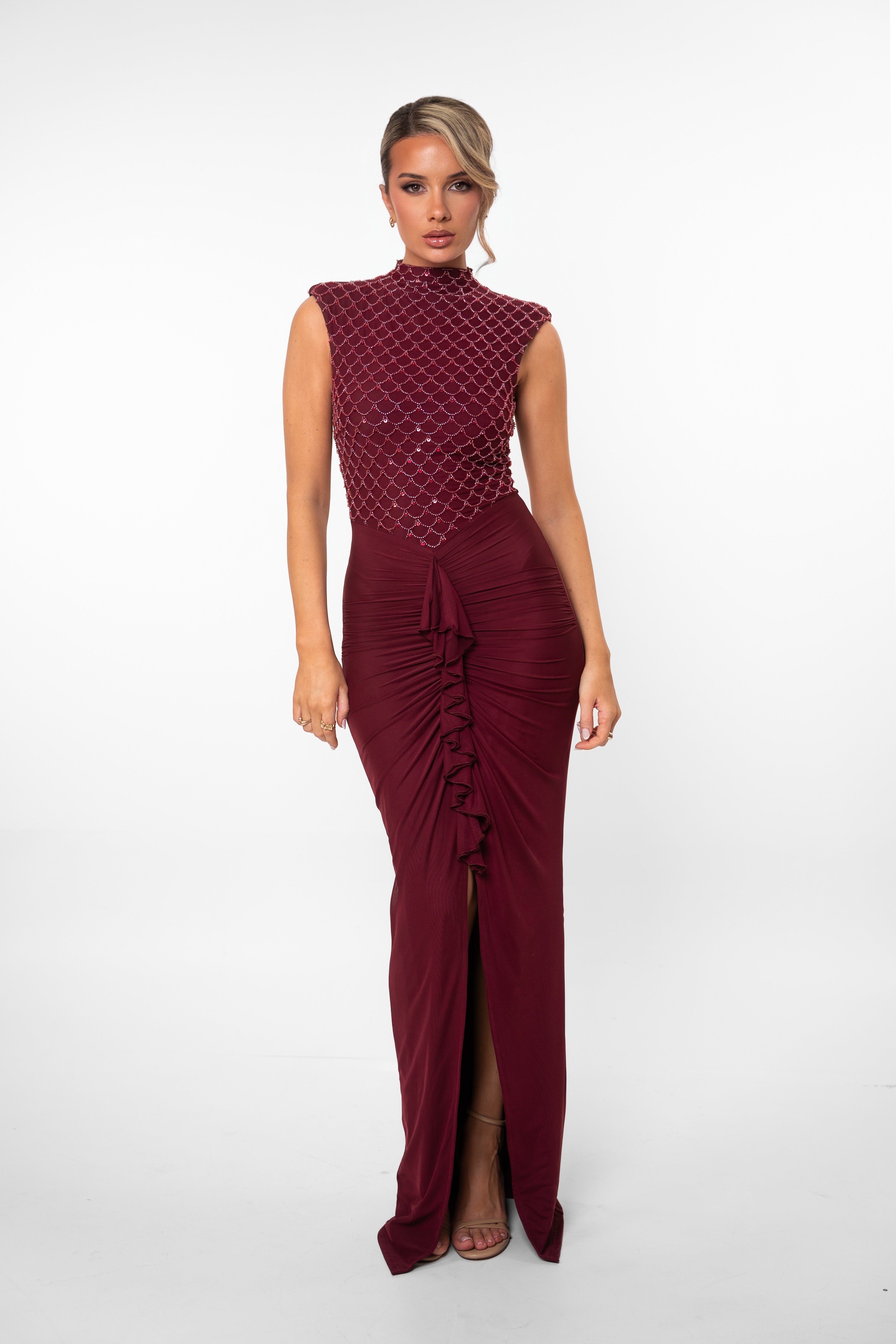 Deep red floor-length gown with embellishments on the top and a ruffled front slit