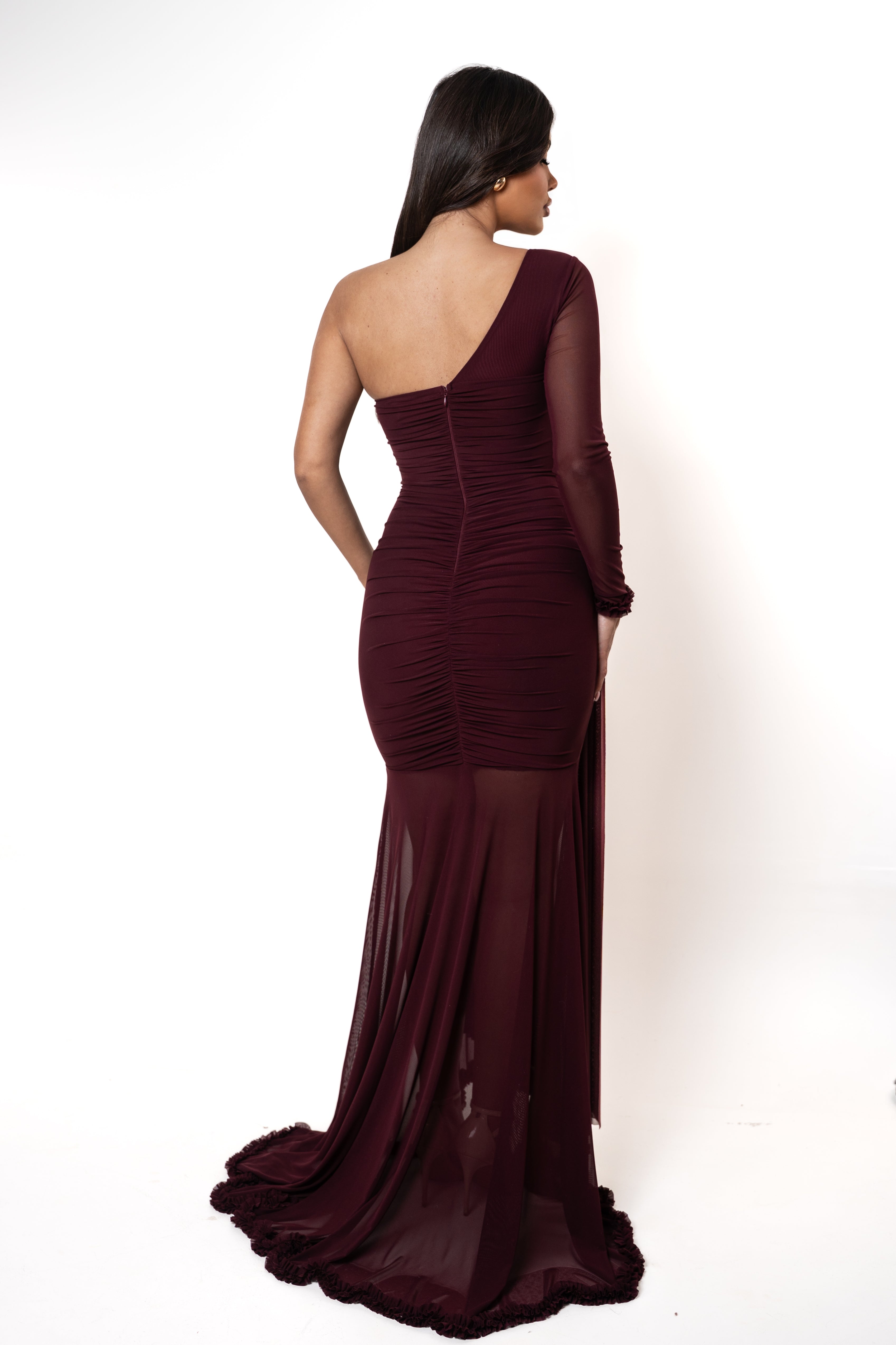 Woman wearing a burgundy one-shoulder evening gown on a white background