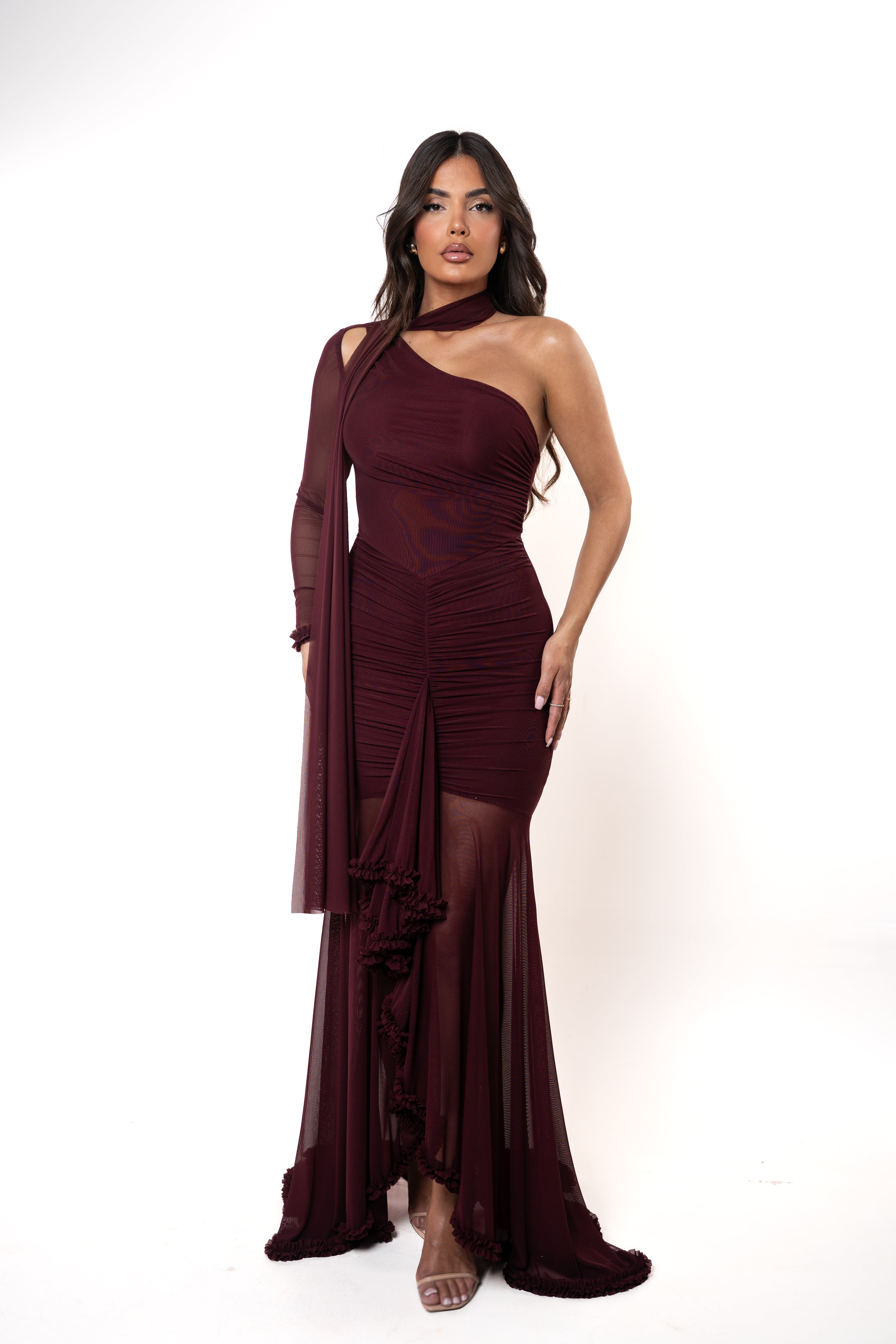 Woman wearing a burgundy one-shoulder dress with a draped effect on a white background