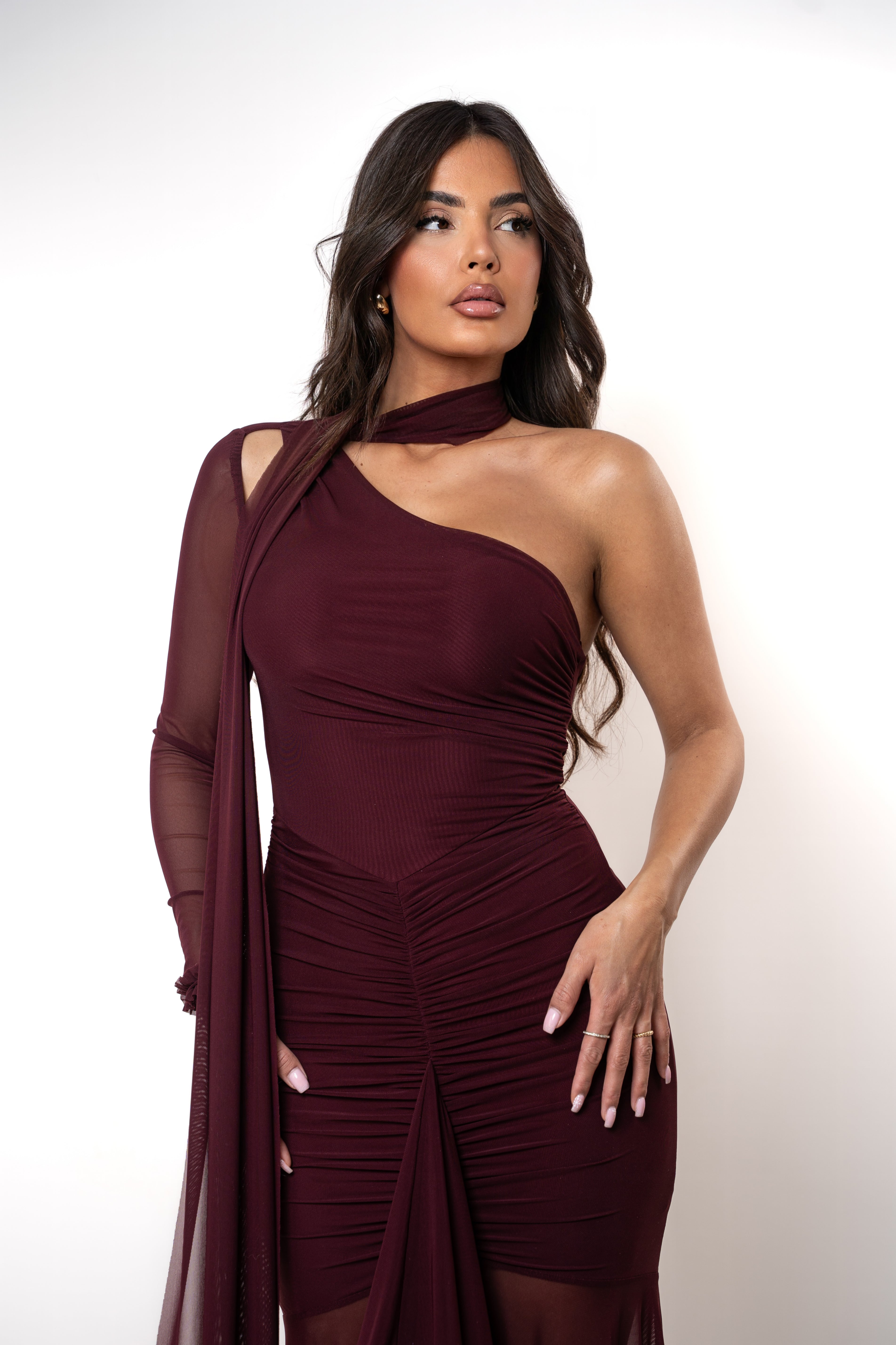 Woman wearing a burgundy one-shoulder dress against a white background