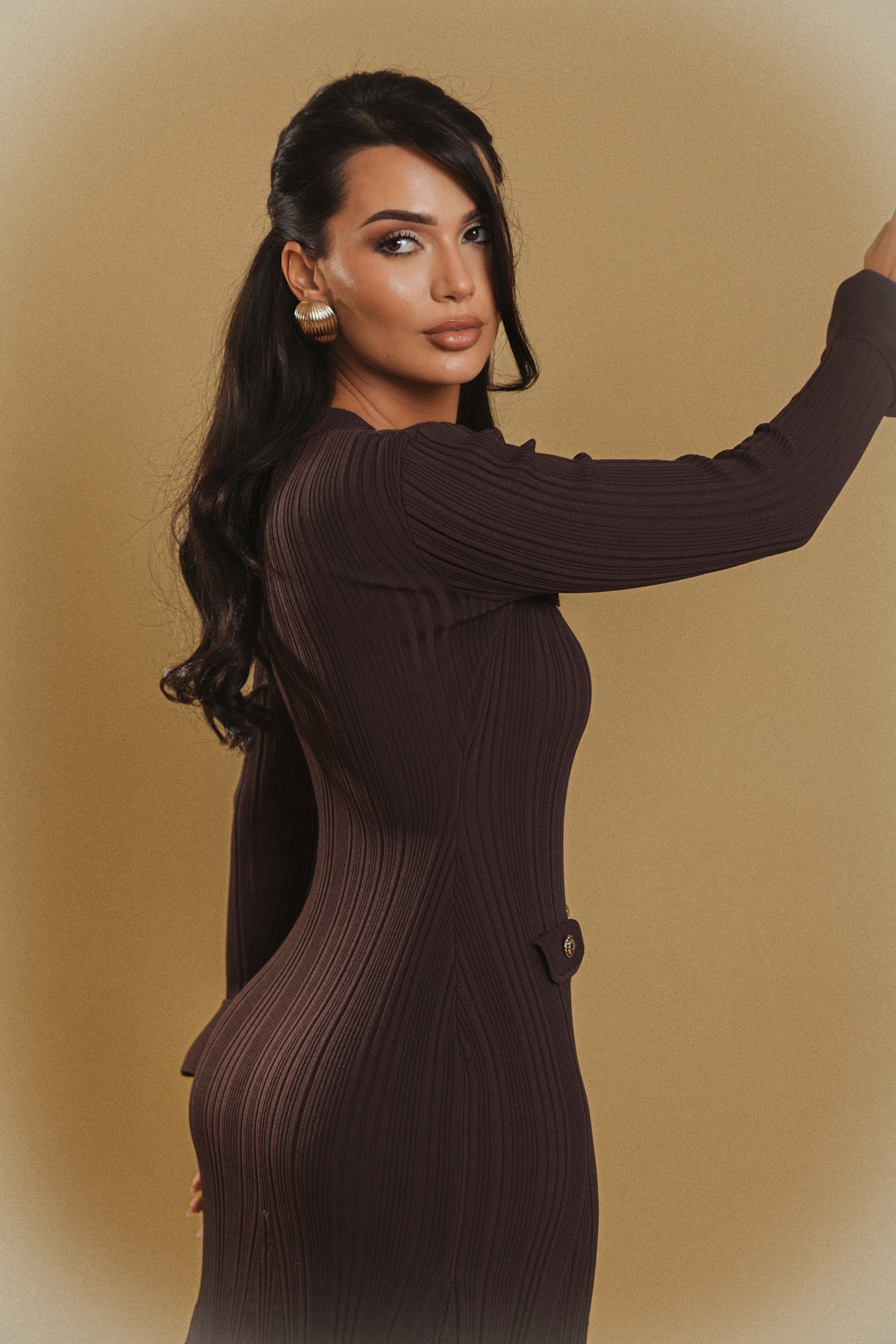Woman wearing a brown ribbed dress against a beige background