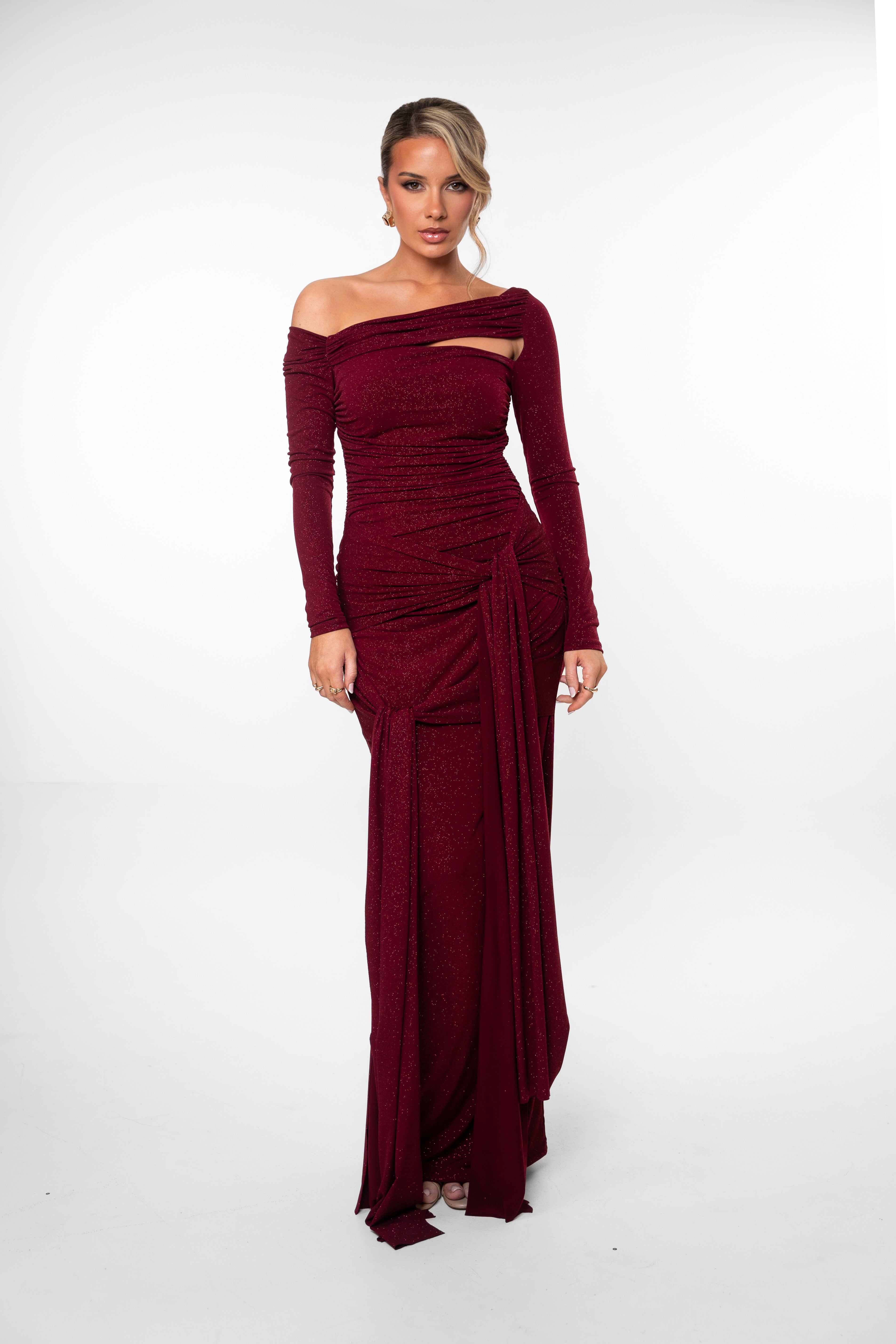 Woman wearing a burgundy off-shoulder gown on a white background