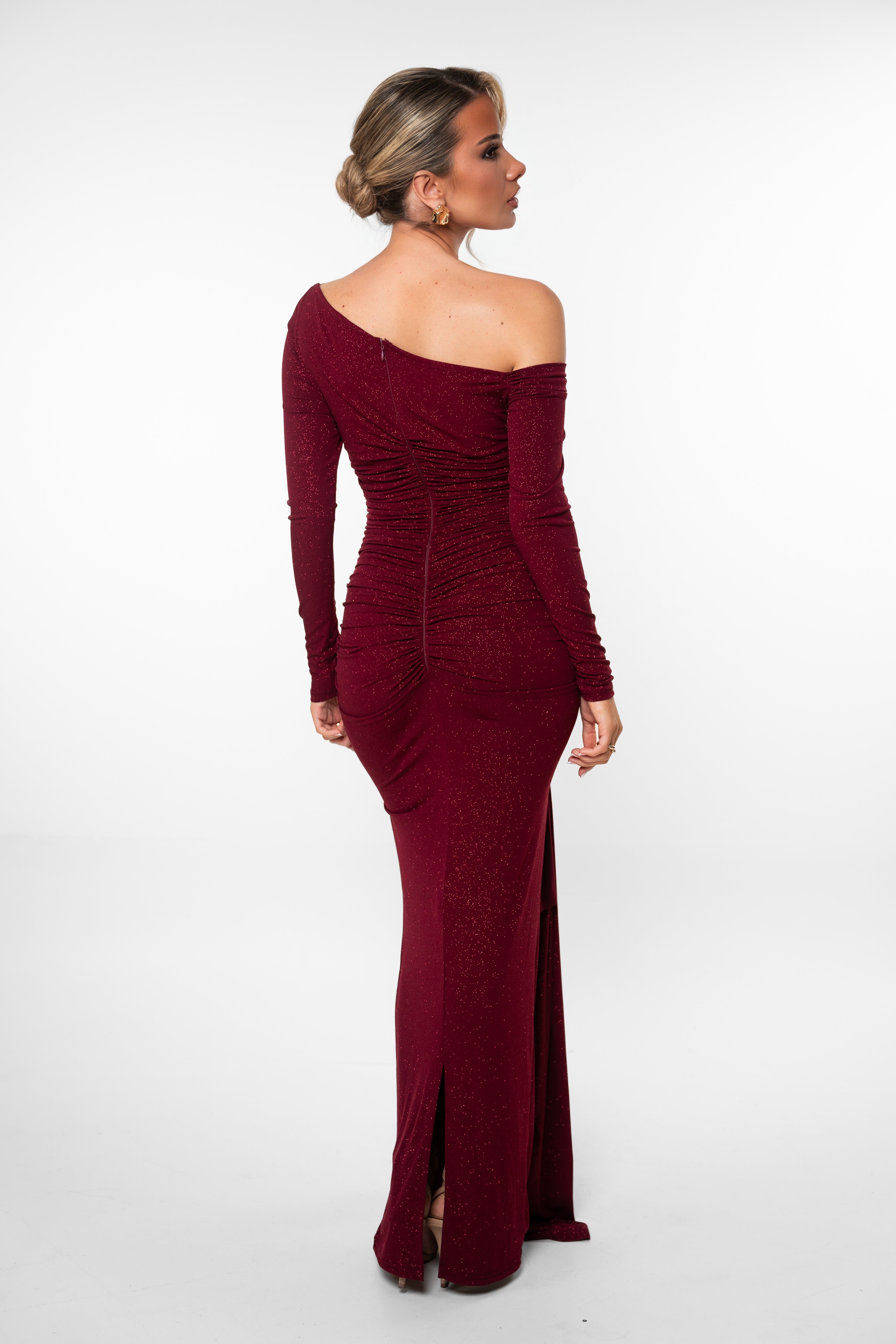 Woman wearing a burgundy one-shoulder dress on a white background