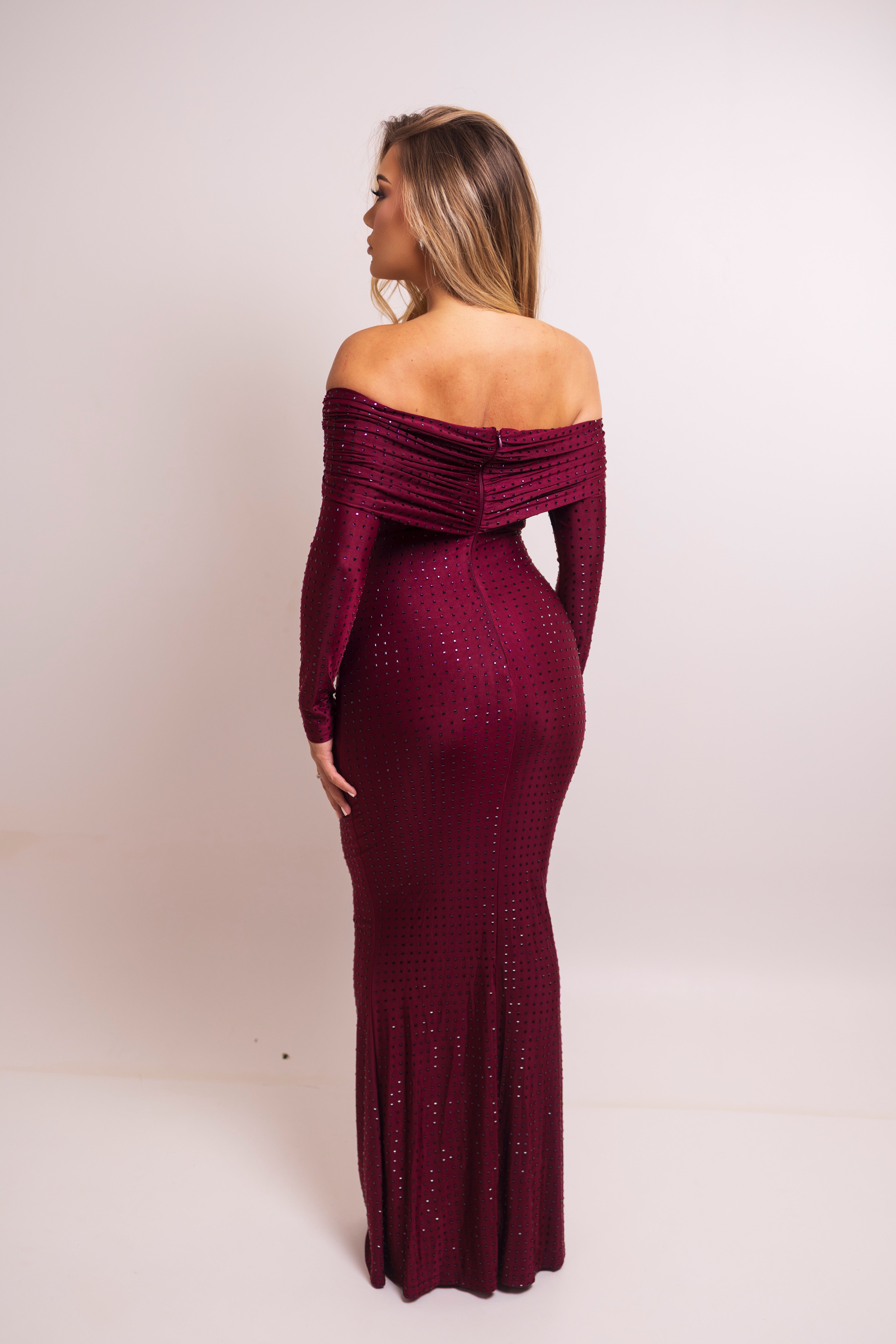 Burgundy glitter dress with off-shoulder design, long sleeves, and ruched details.