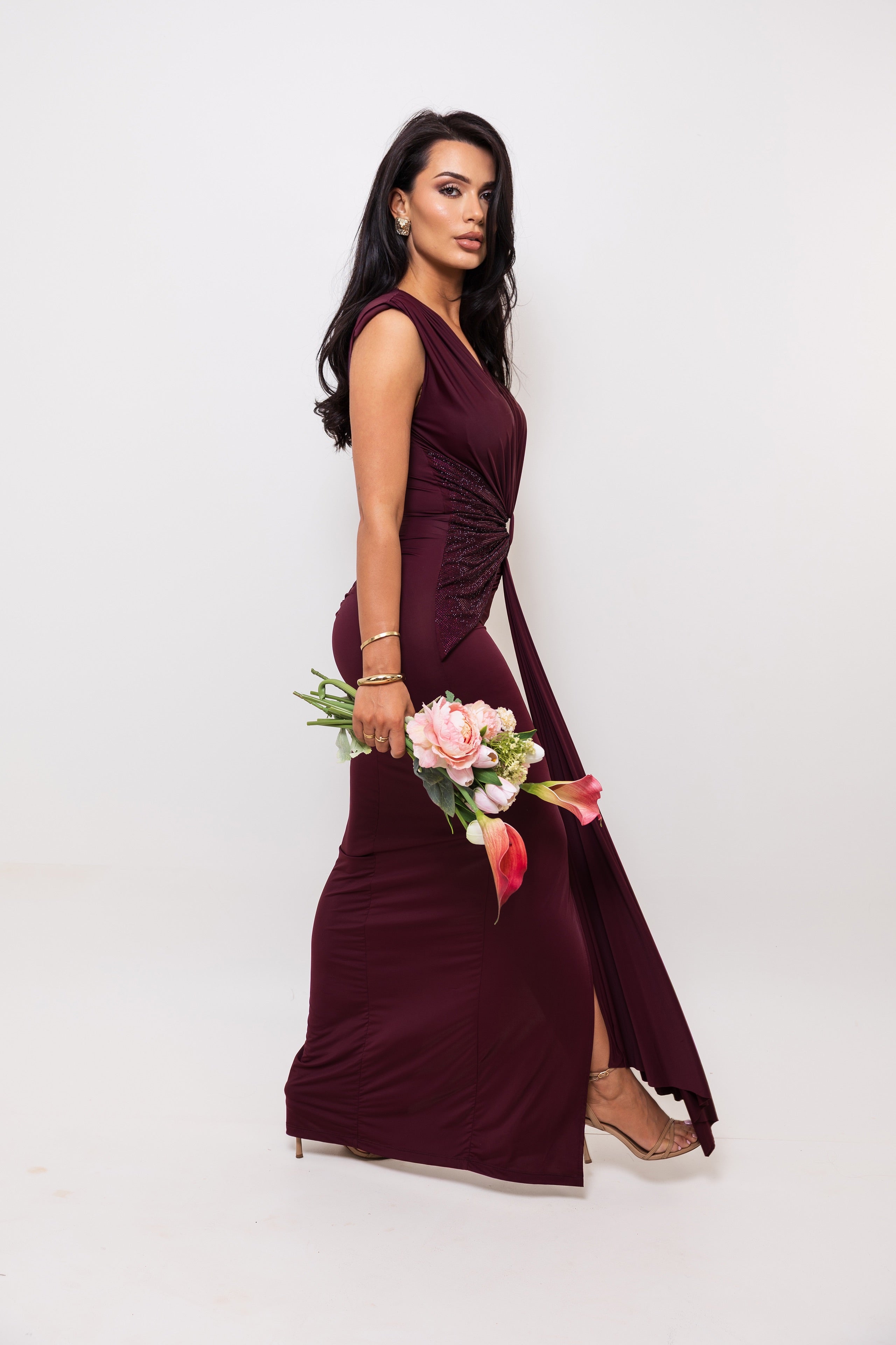 Woman in a burgundy dress holding flowers against a white background