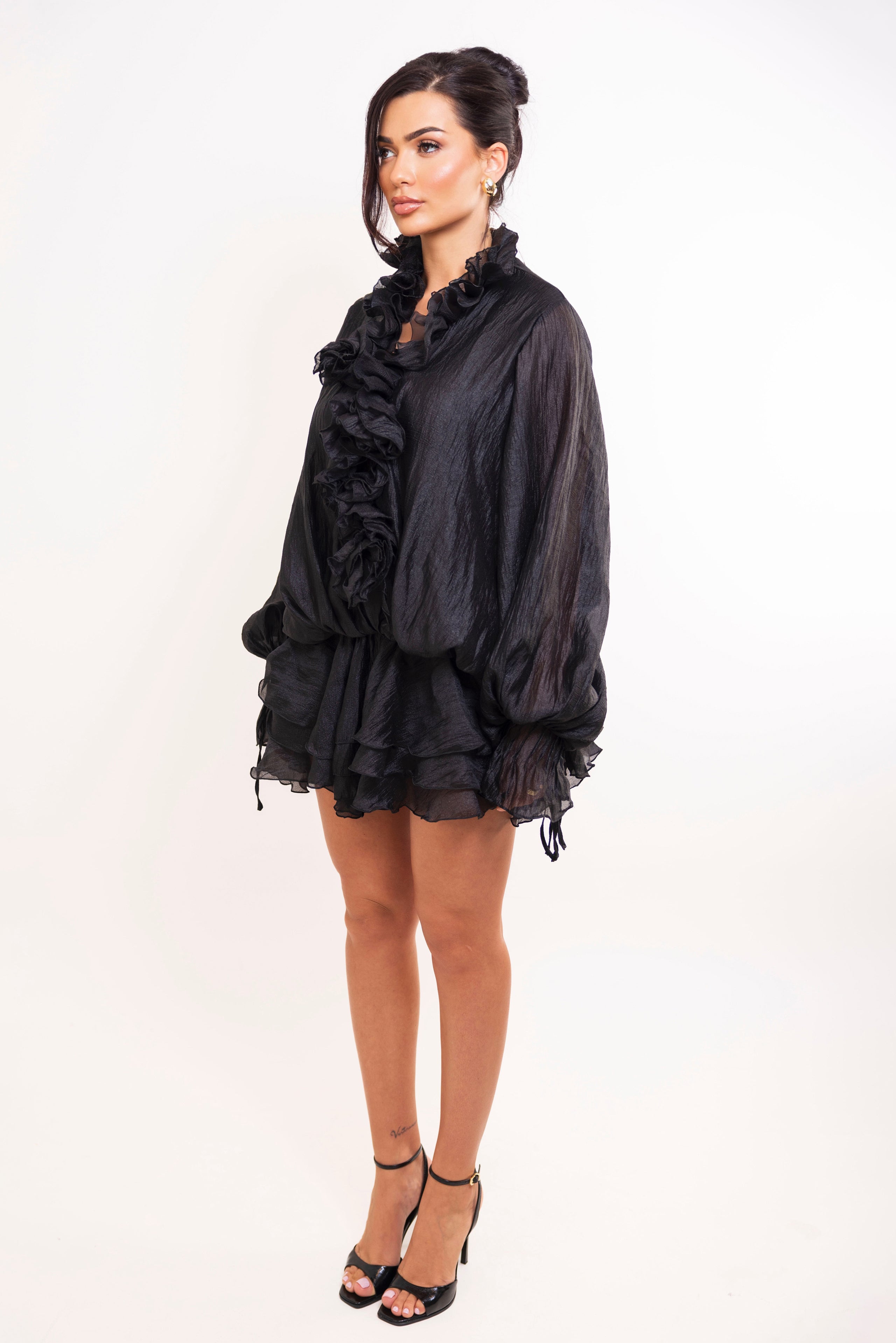 Back view of flowy black ruffle dress featuring layered skirt and puffed sleeves.