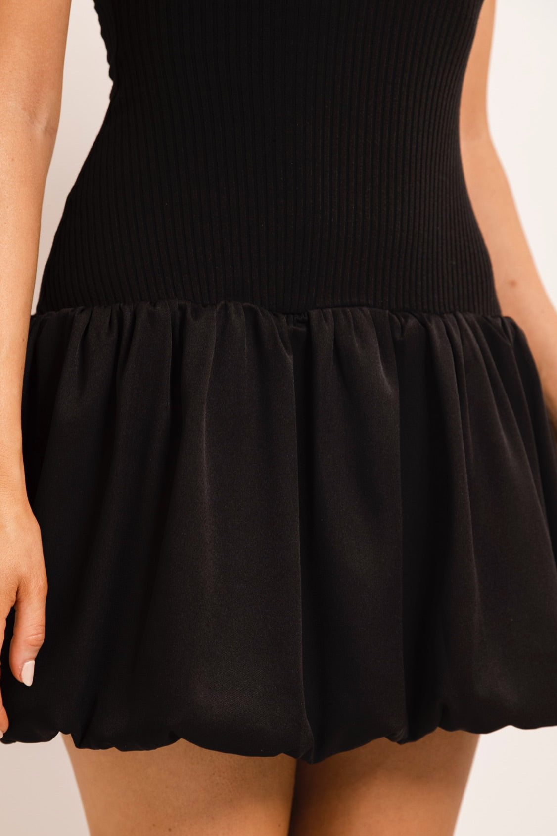 Modern black dress with a structured silhouette and playful hem.