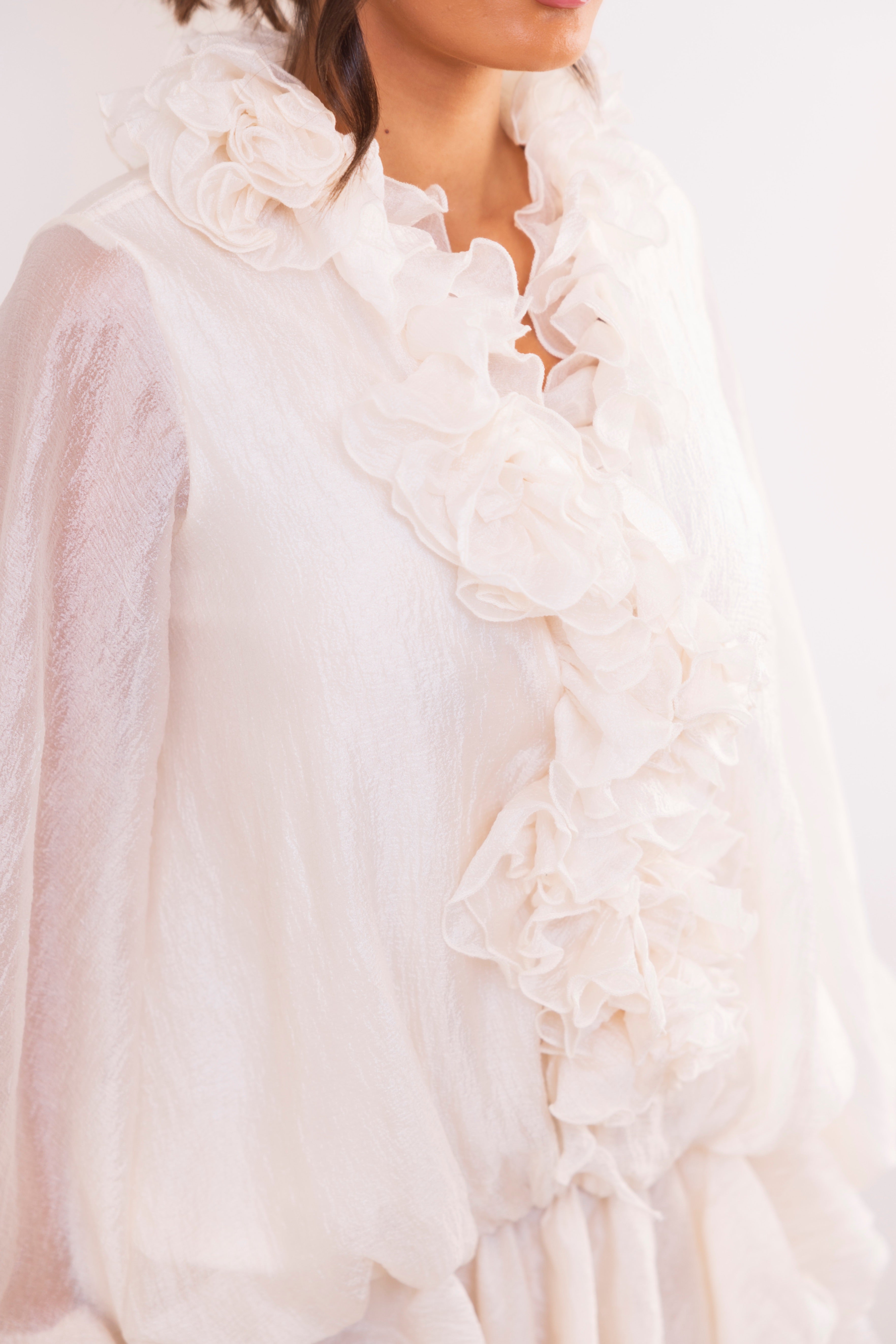 Close-up of a white ruffled detail on a person against a white background