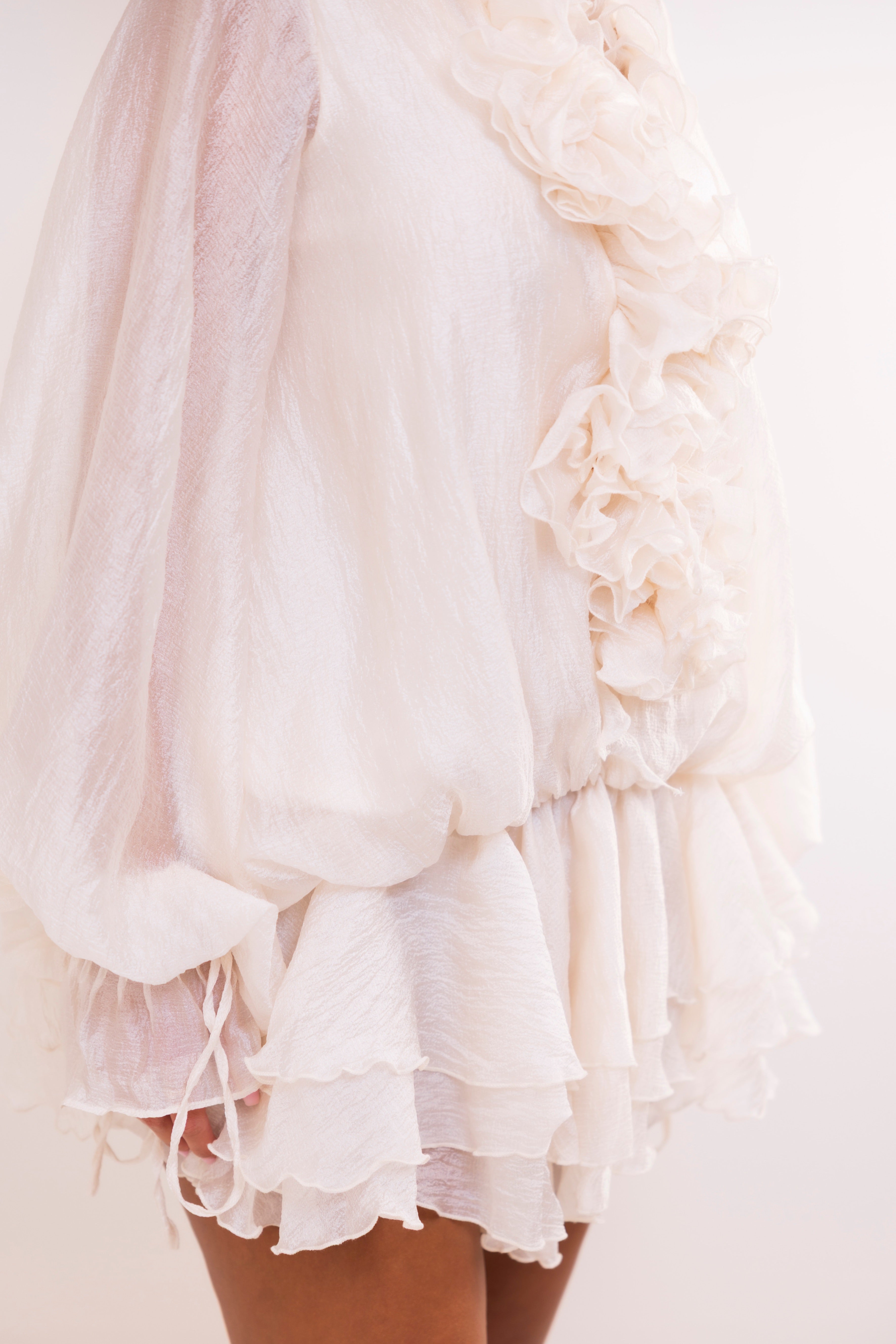 Close-up of a light color ruffled dress on a plain background