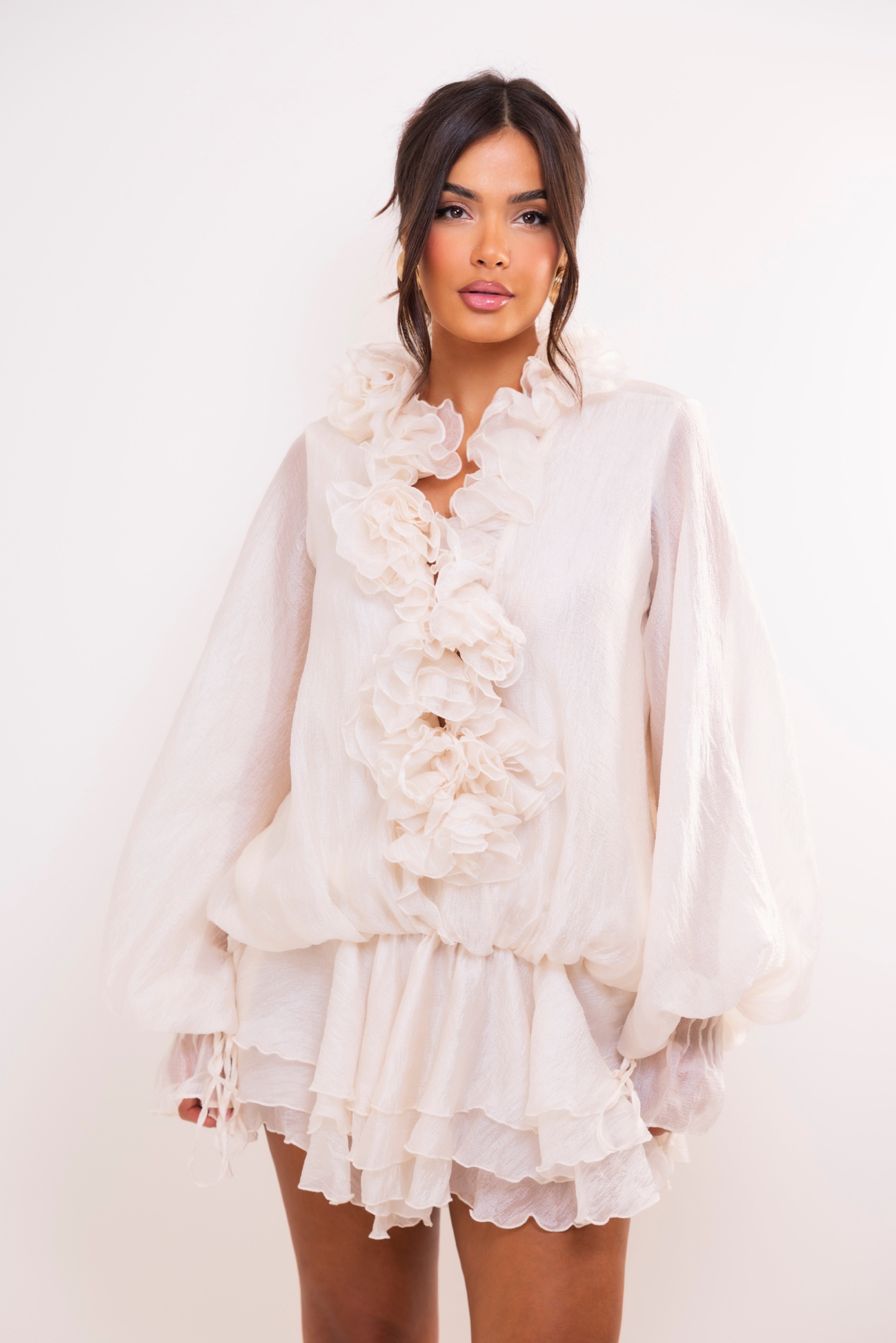 Woman wearing a white ruffled dress against a white background