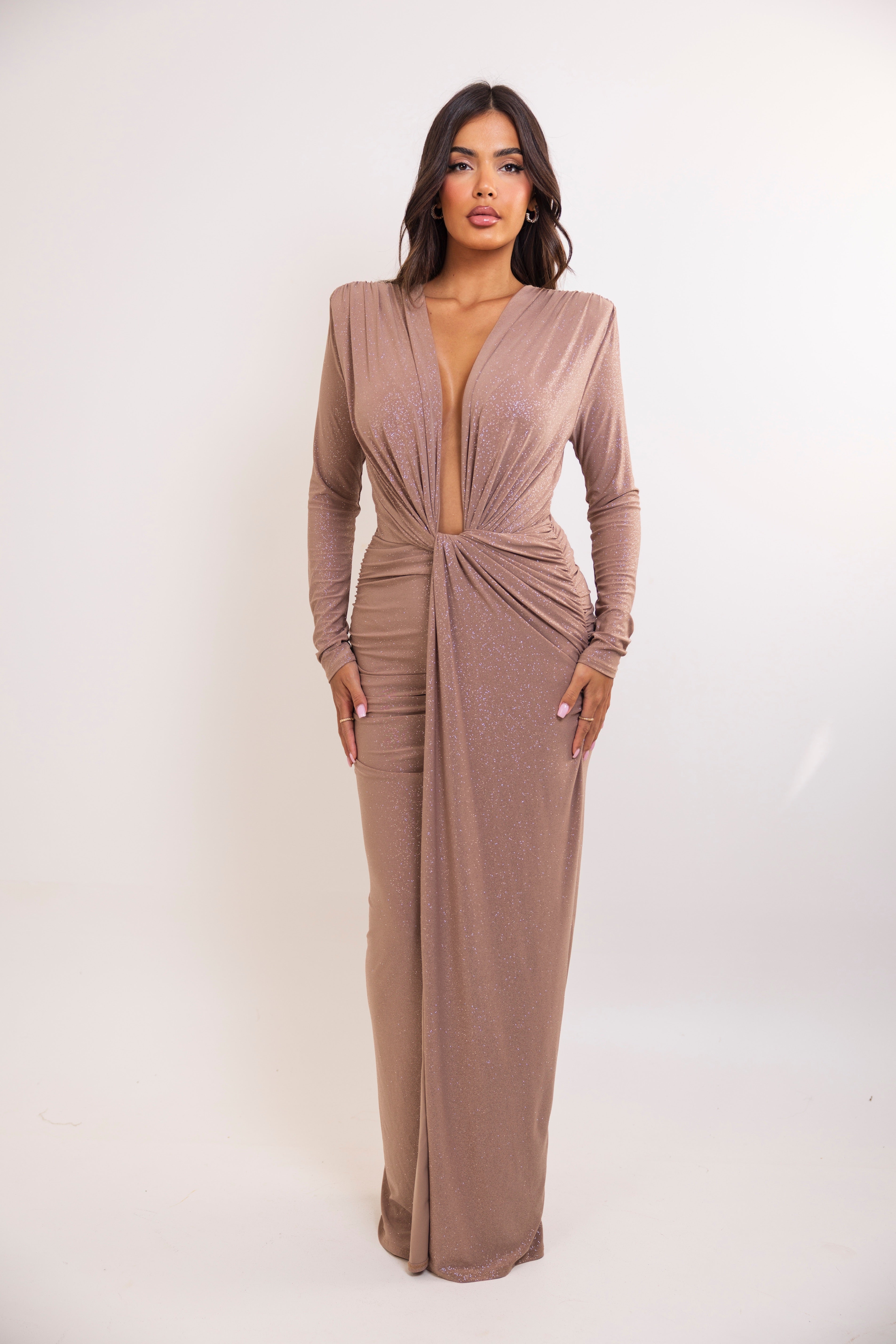 Woman wearing a long brown dress with a plunging neckline on a white background