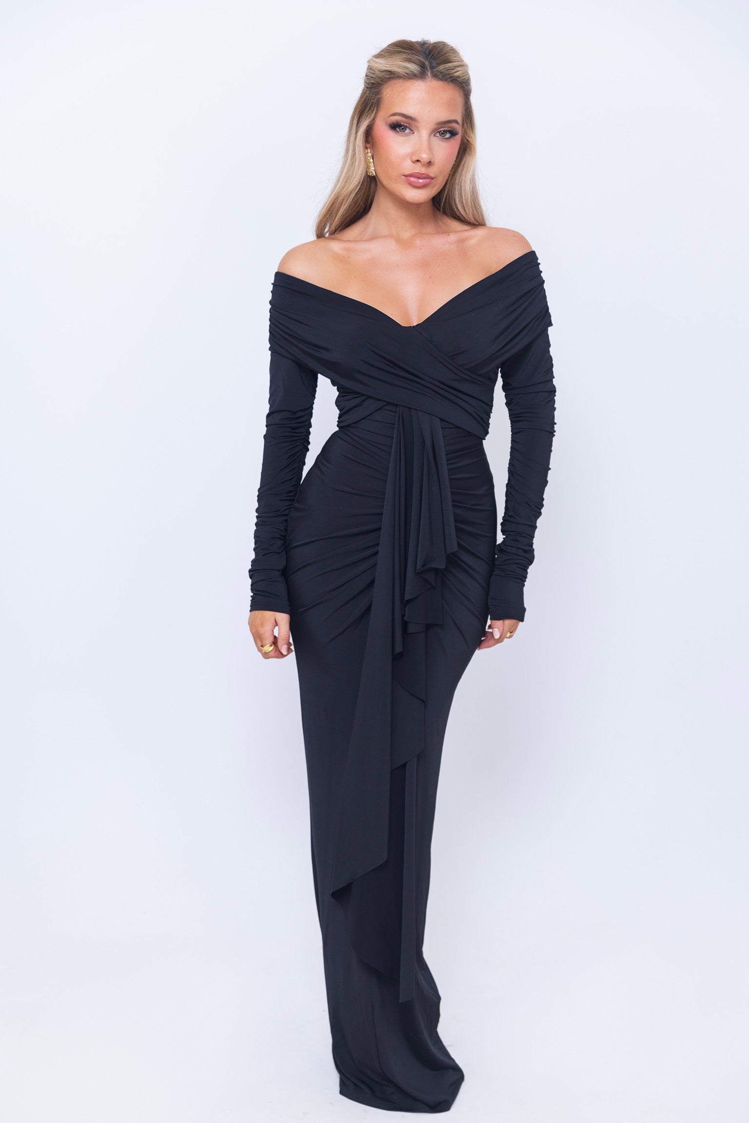 Figure-hugging black evening gown with a bold off-the-shoulder cut and draped finish.