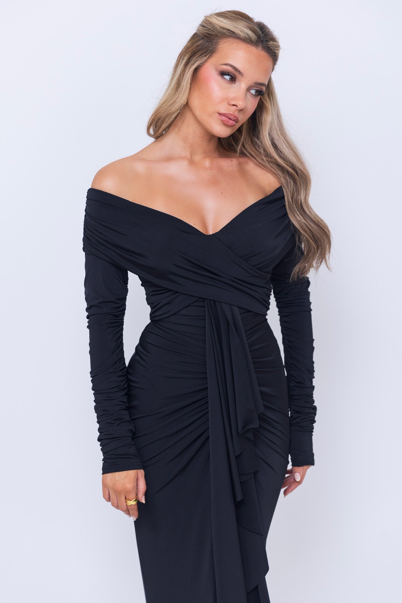 Chic black dress with gathered fabric, long sleeves, and a statement drape.