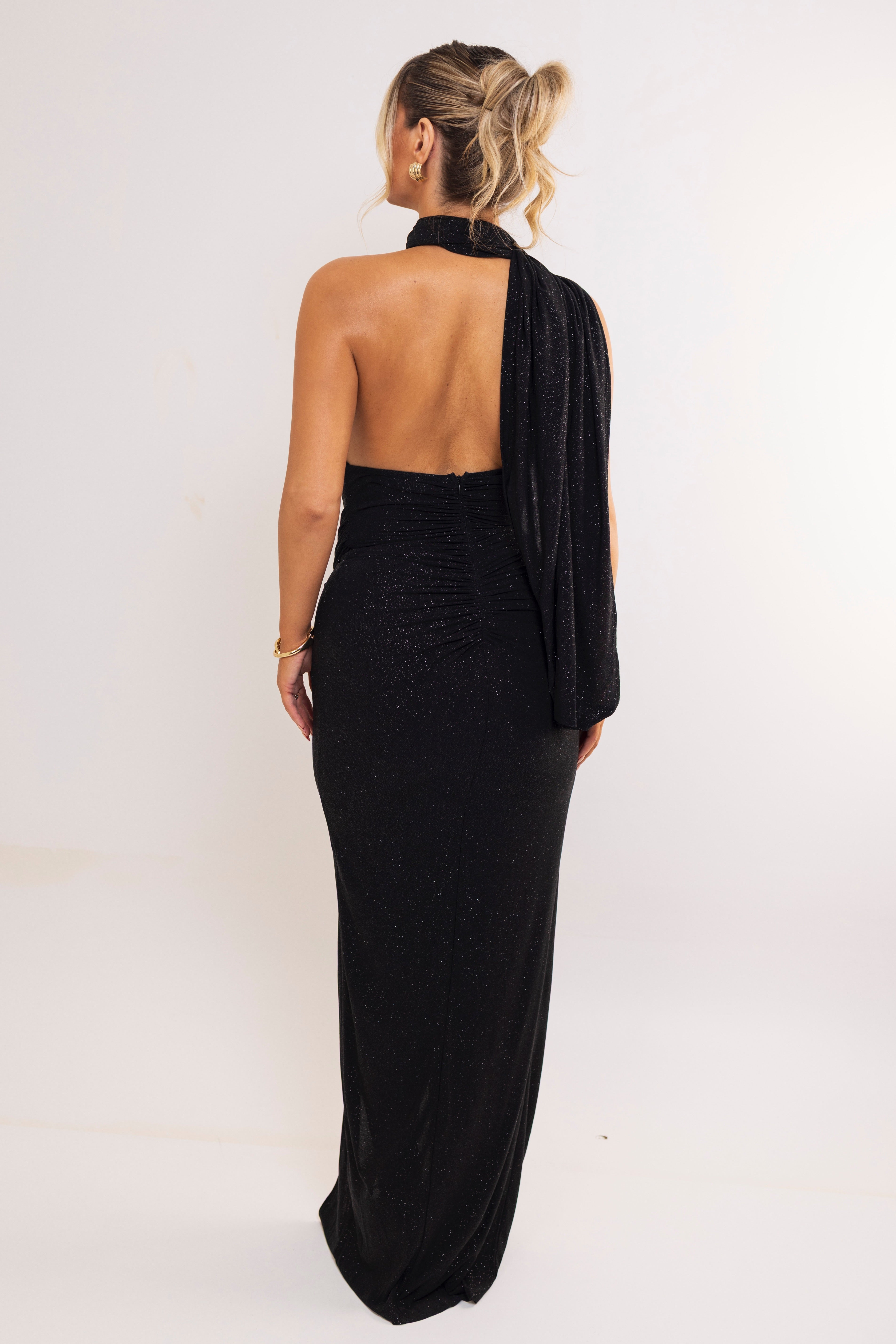 Form-fitting black glitter dress with ruched detailing.