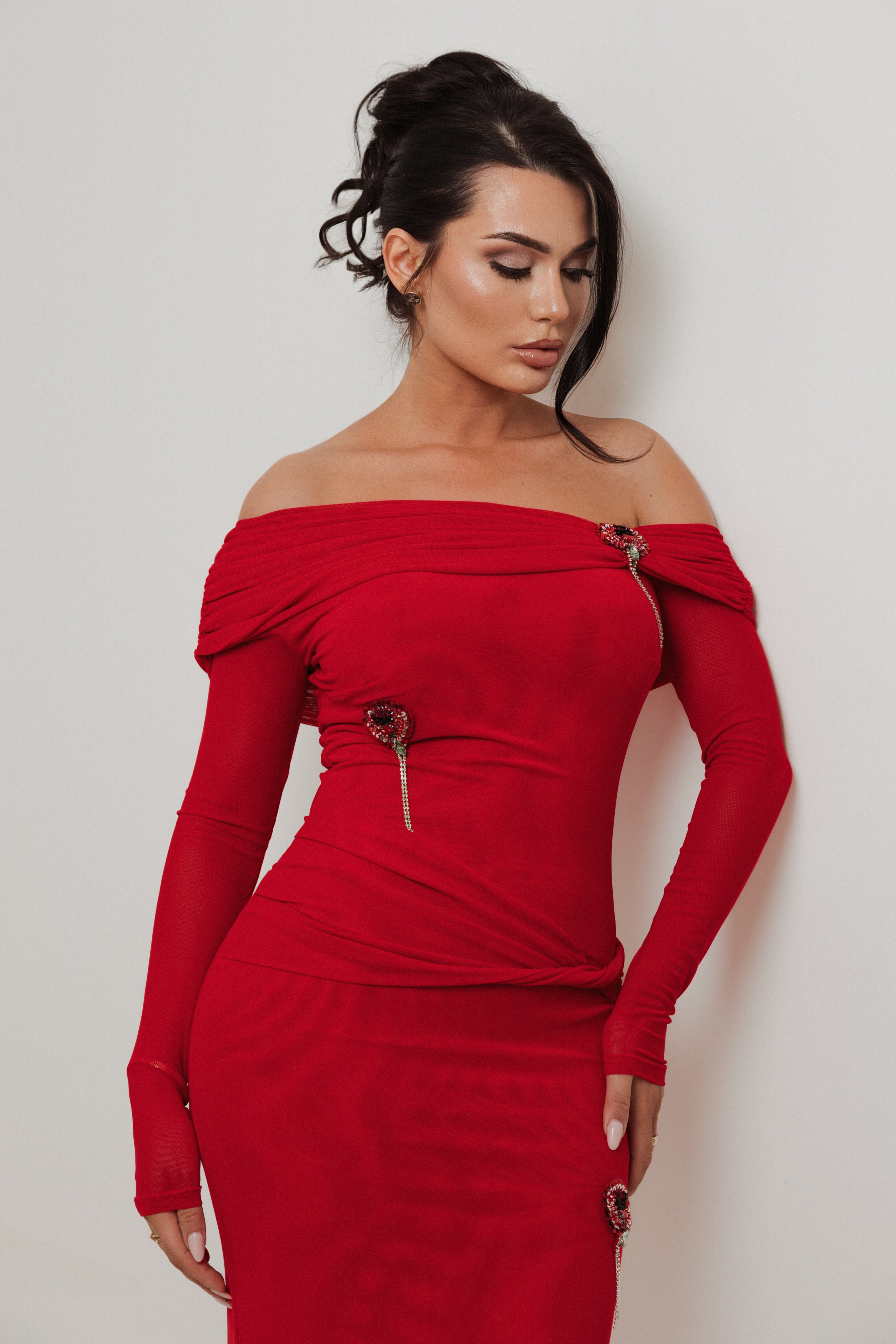 Woman wearing a red off-shoulder dress against a plain background