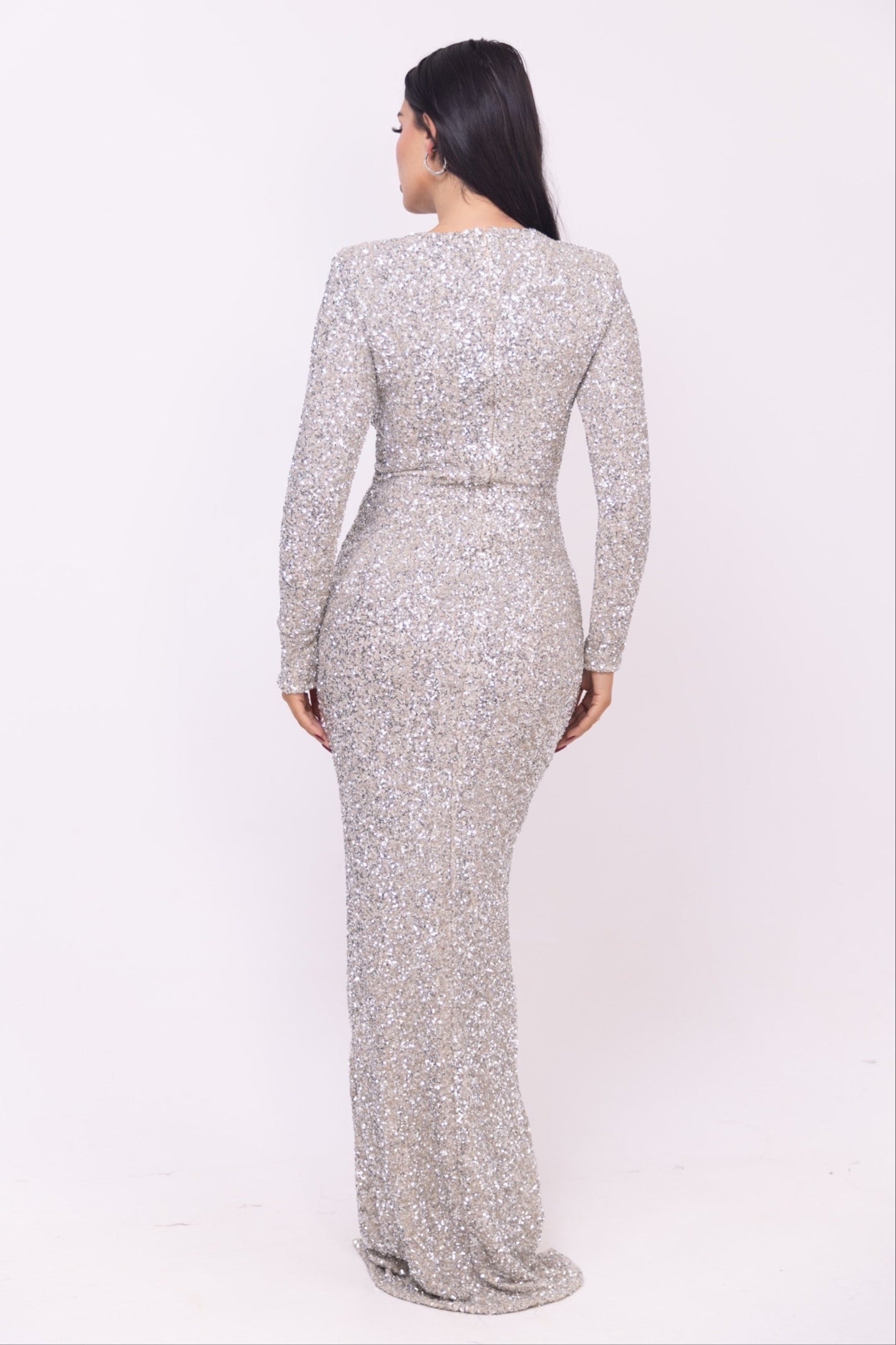 Woman in a shimmering silver dress with long sleeves and a thigh-high slit