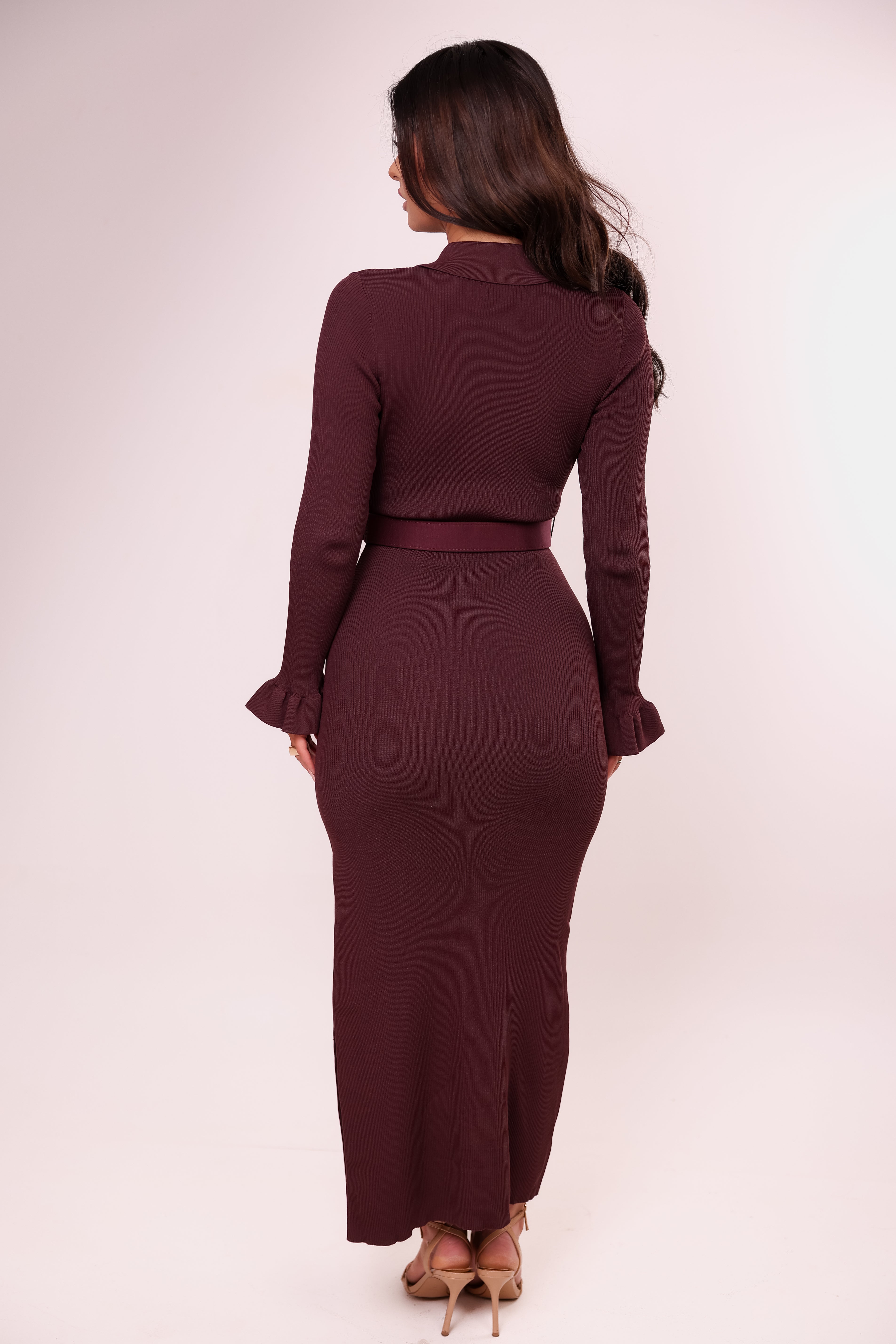 Woman wearing a burgundy dress with long sleeves on a white background