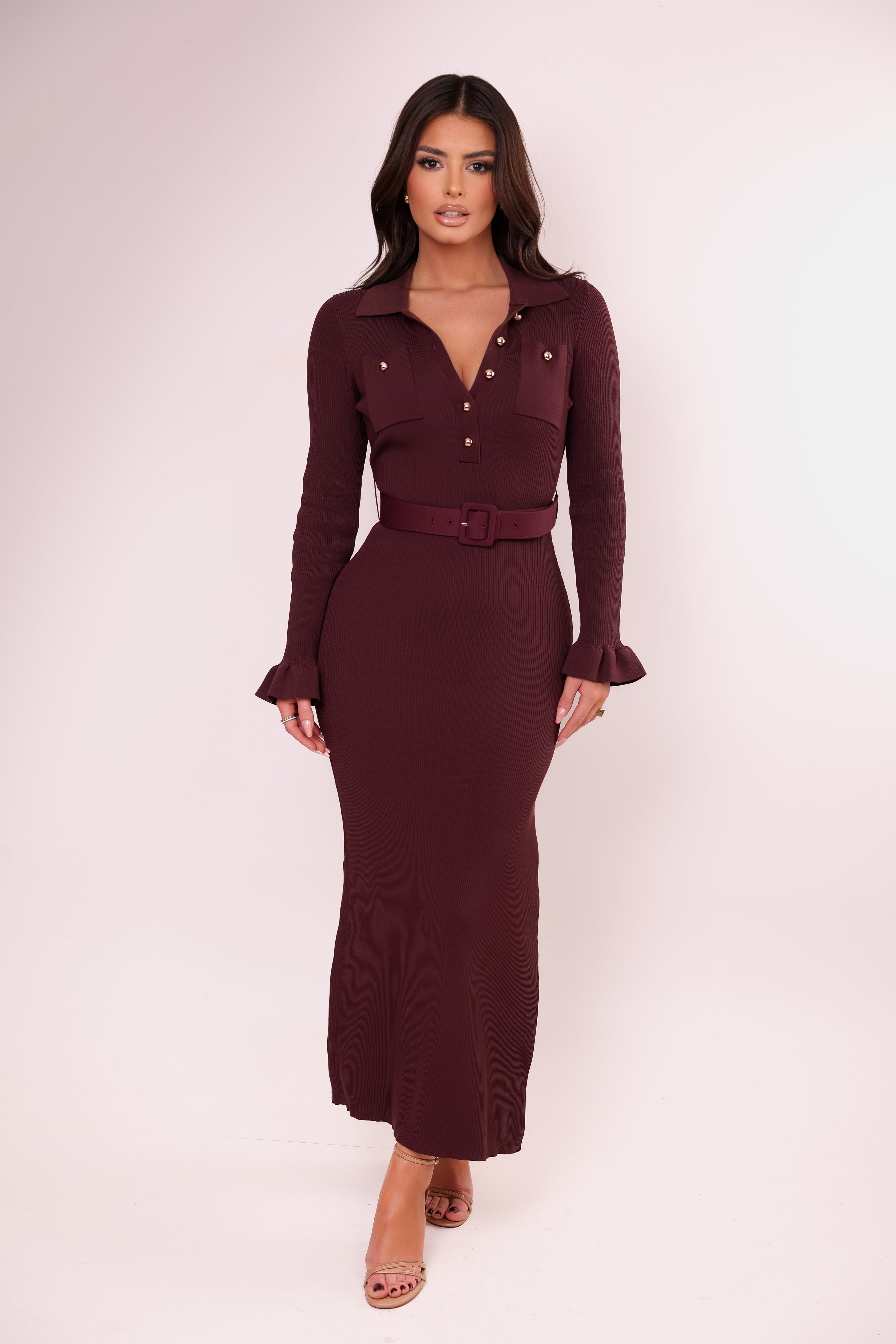 Woman wearing a burgundy dress with a belt against a white background