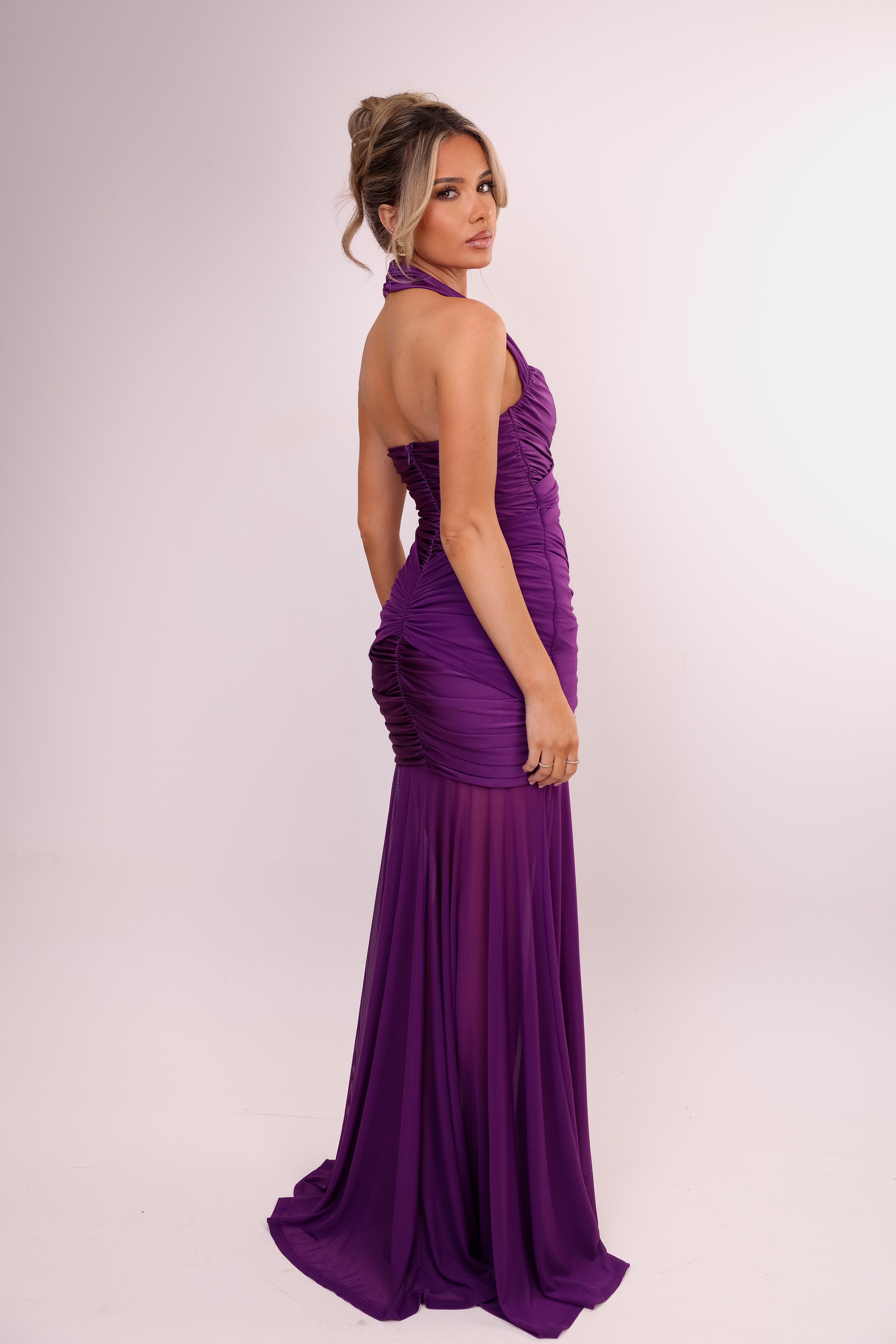 Woman wearing a purple evening gown on a light pink background