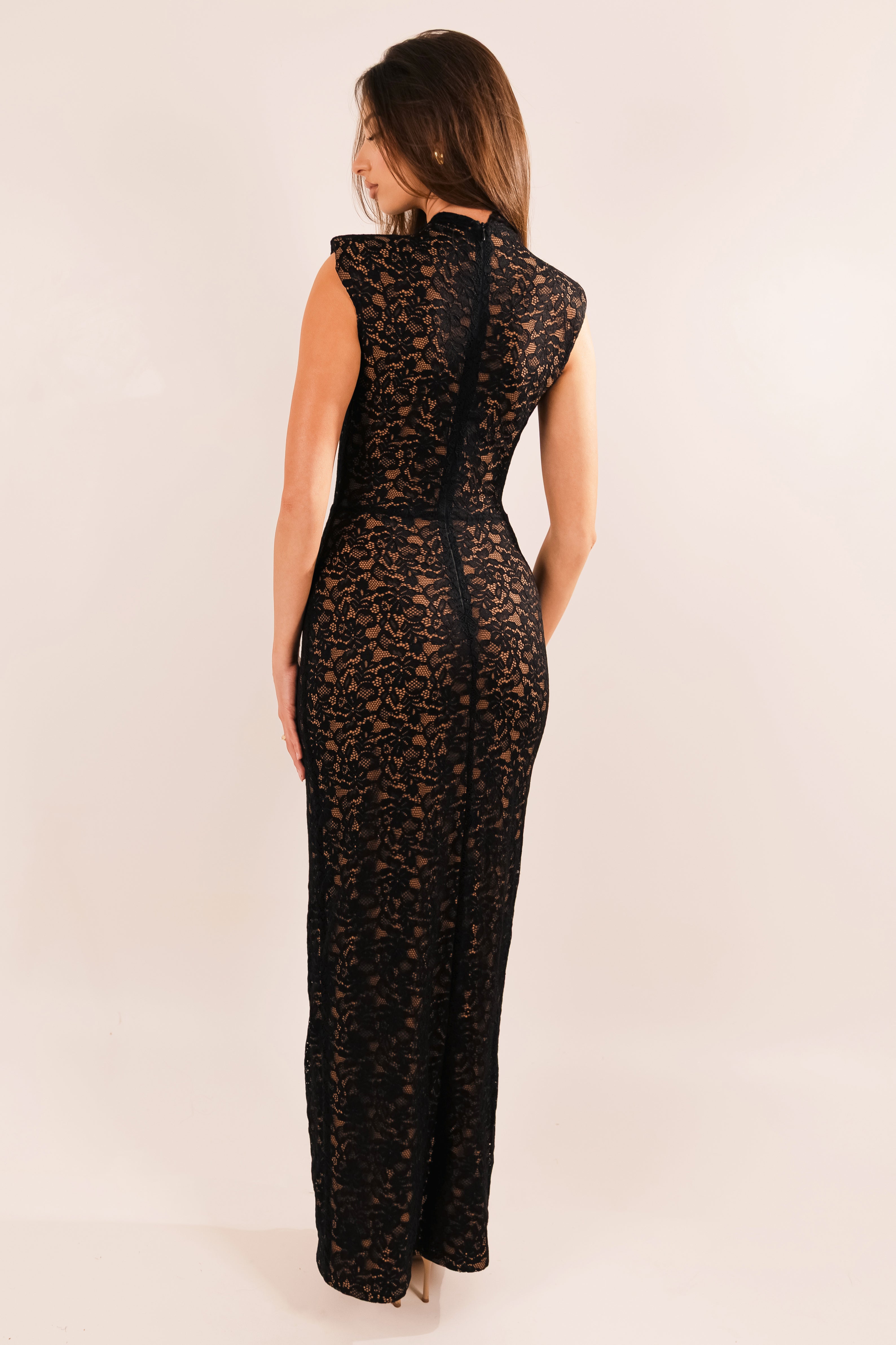 Woman wearing a black lace dress against a plain background