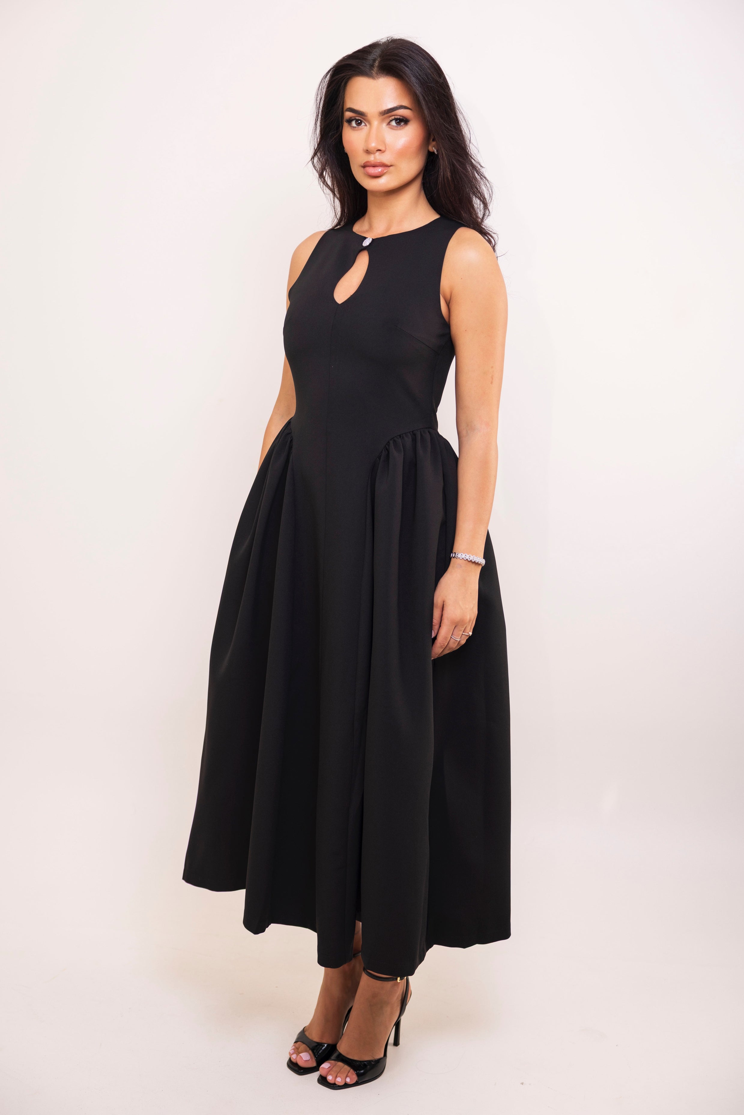 Front view of elegant black A-line dress featuring gathered waist detail.