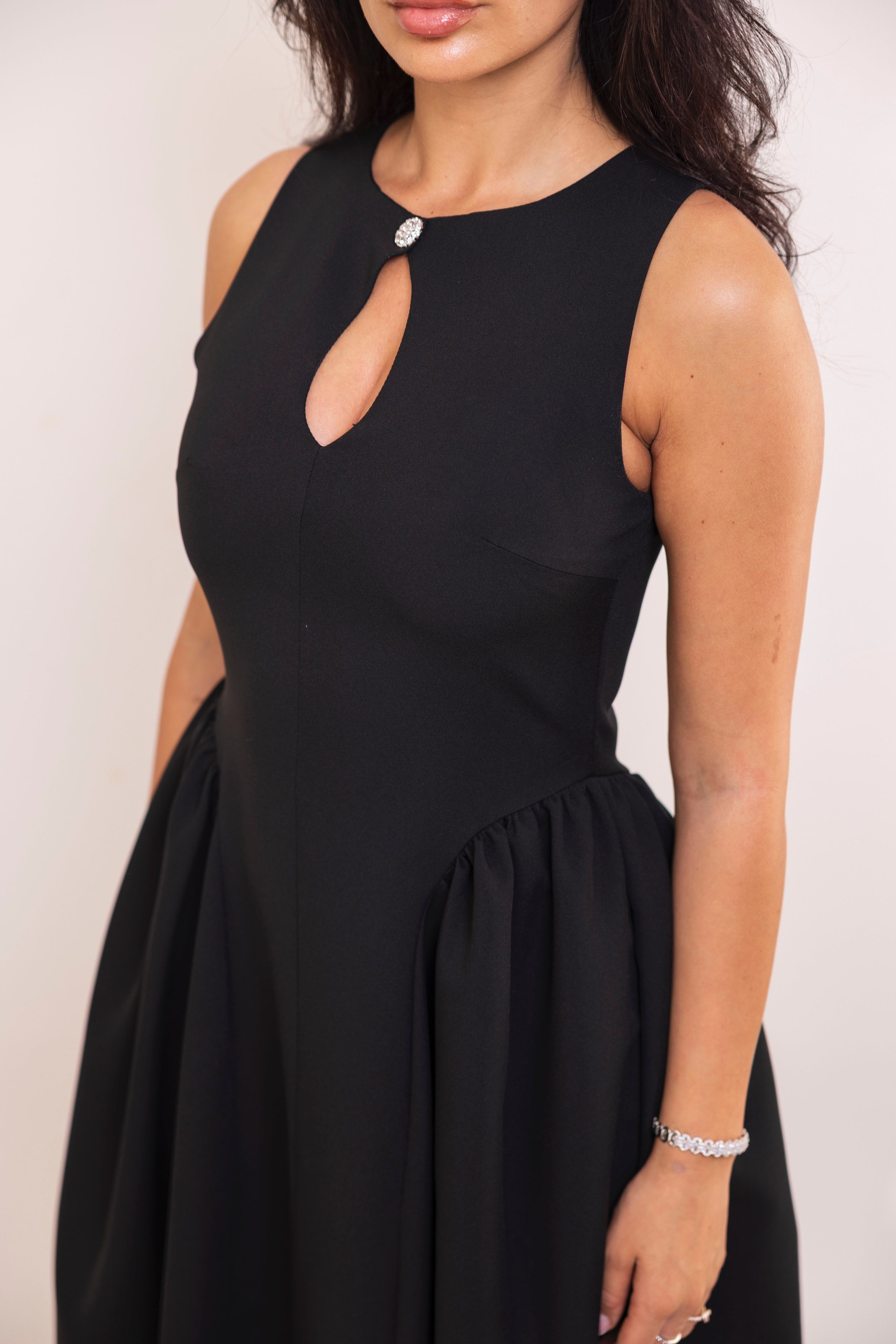 Sophisticated sleeveless black dress with structured silhouette and flowy hem.