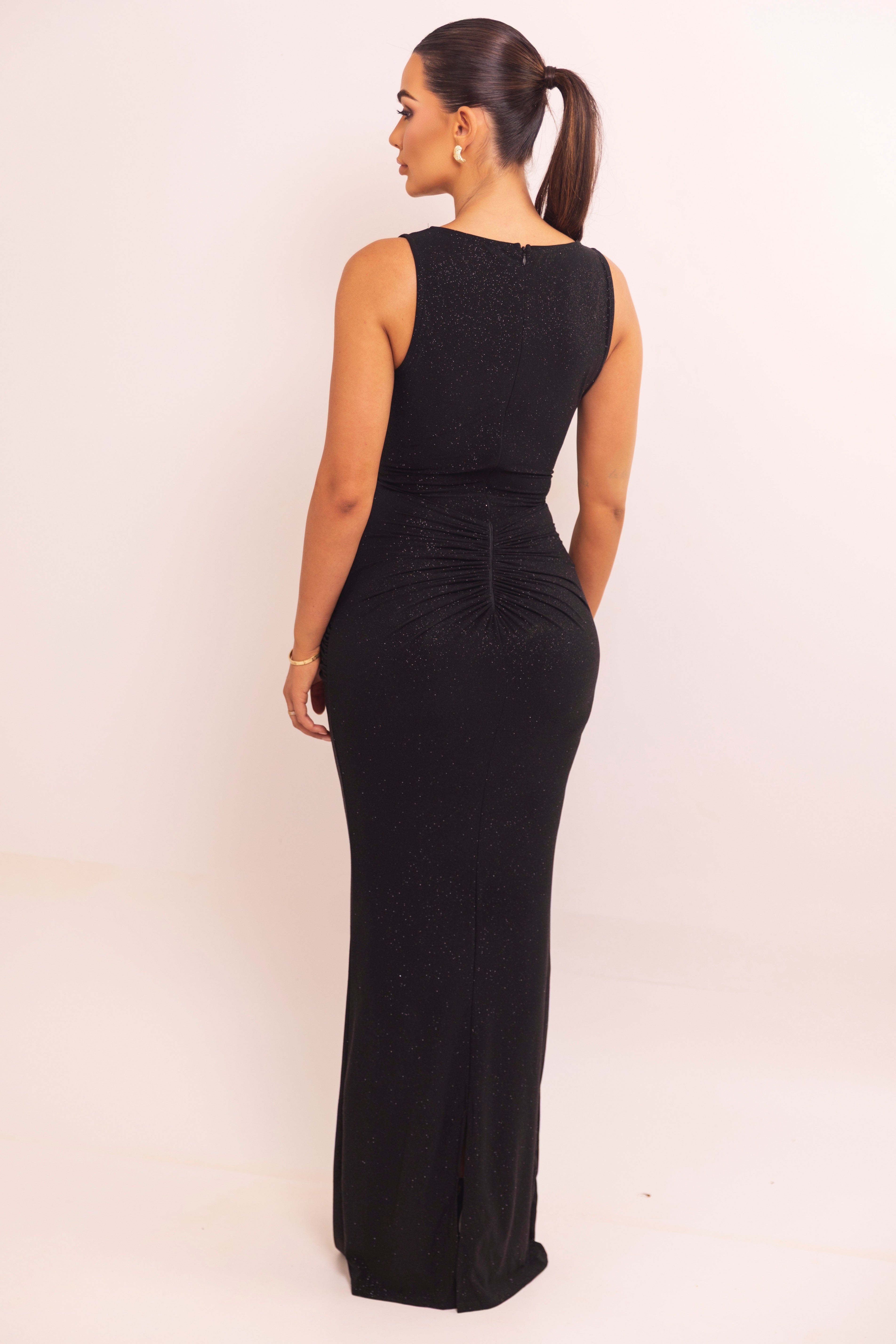 Back view of a sleeveless black floor-length dress with subtle shimmer and gathered seam detailing.