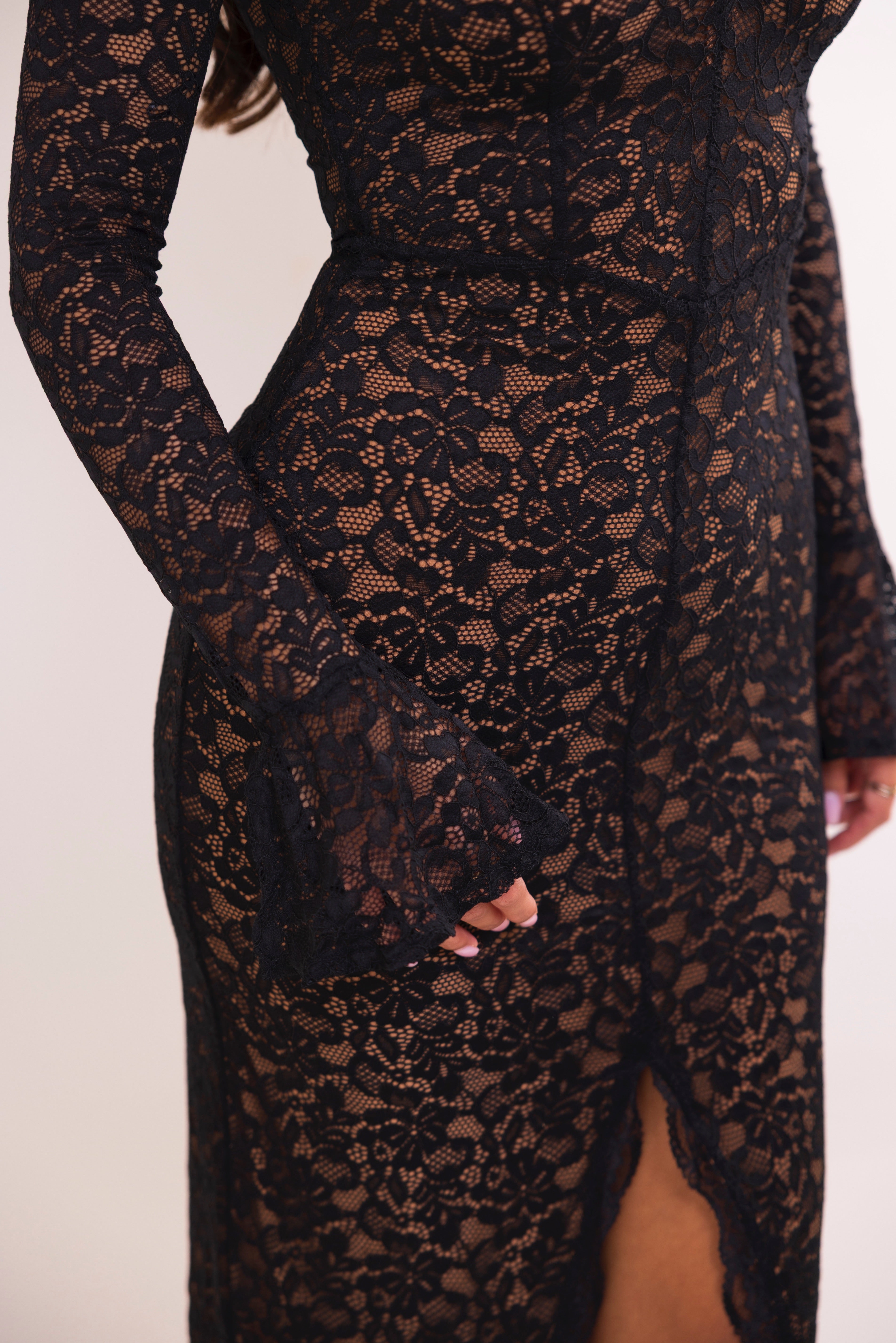 Back view of a fitted black floral lace dress with center-back seam and subtle flare at the cuffs