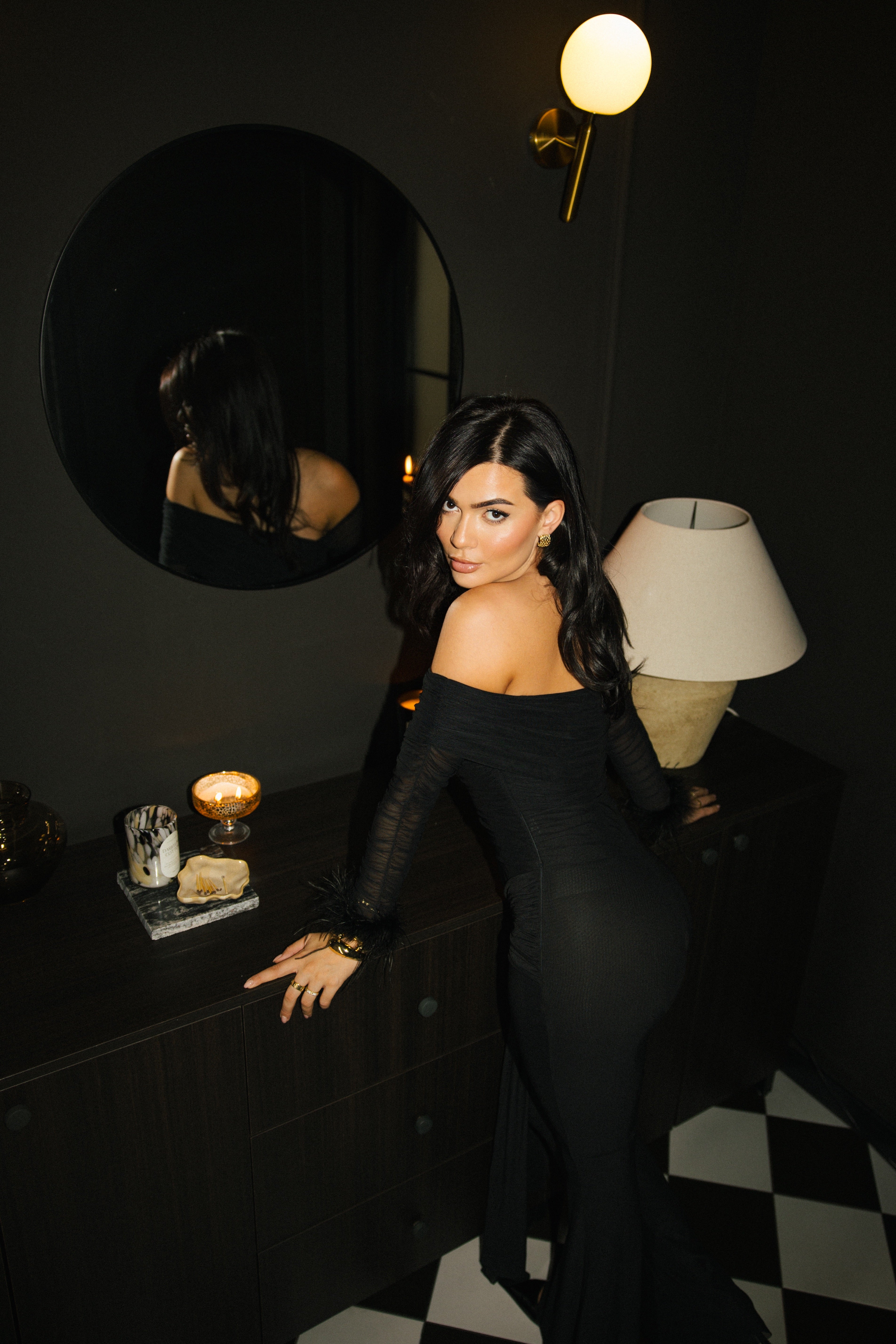 Full view of off-shoulder black jumpsuit styled with pointed heels.