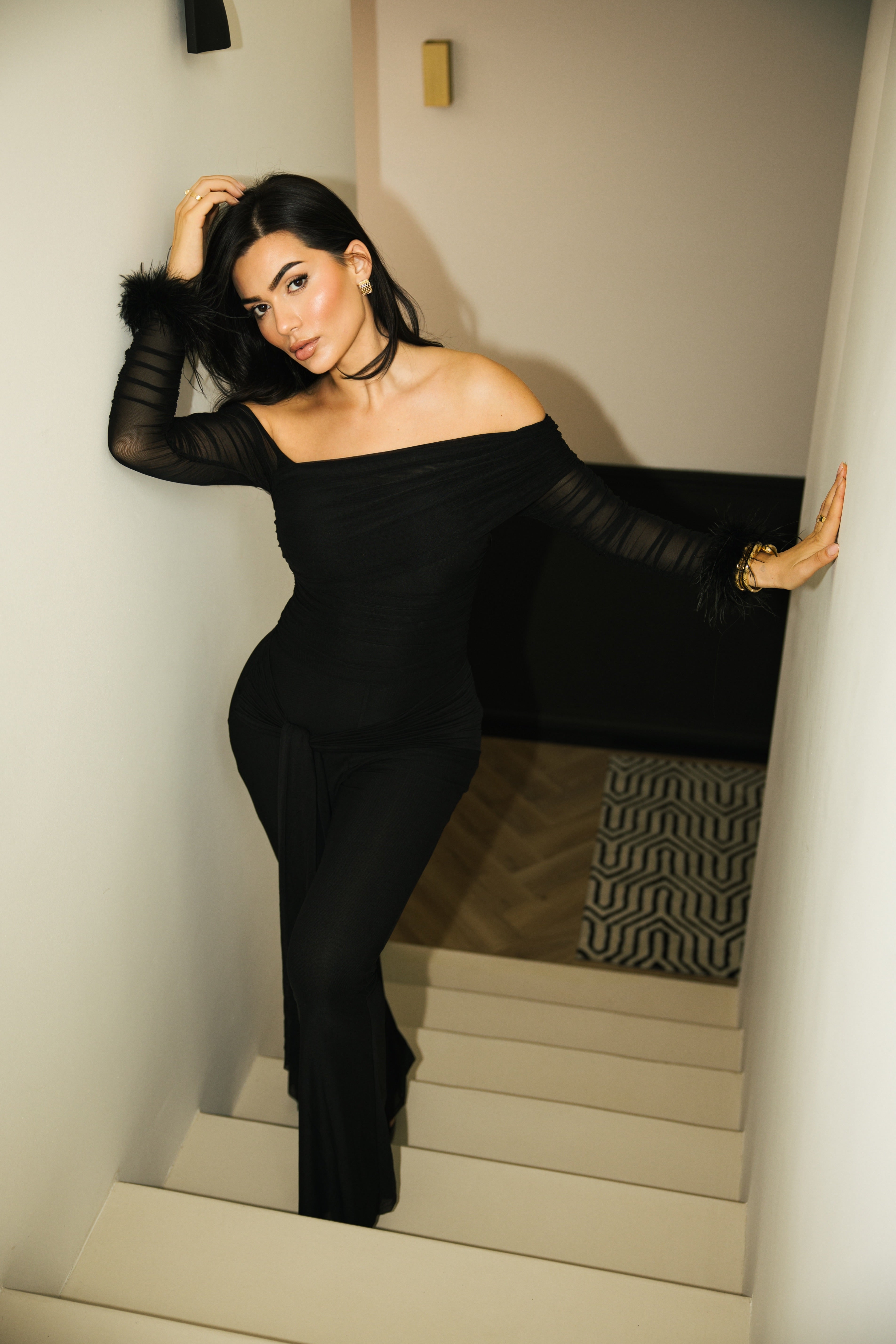 Black evening jumpsuit with ruched detailing and sheer long sleeves.