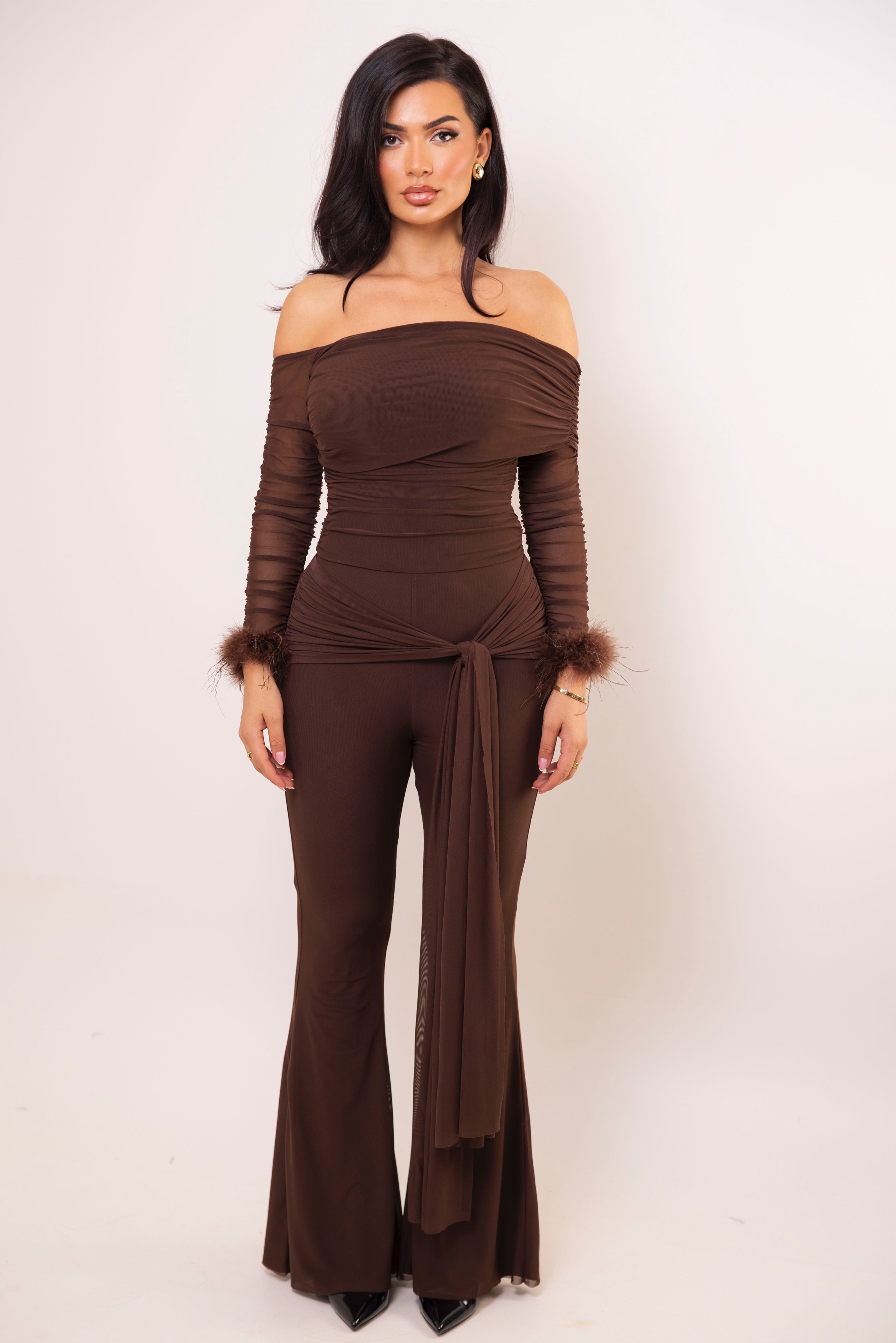 Chocolate brown off-shoulder jumpsuit with ruched mesh bodice and long sleeves.