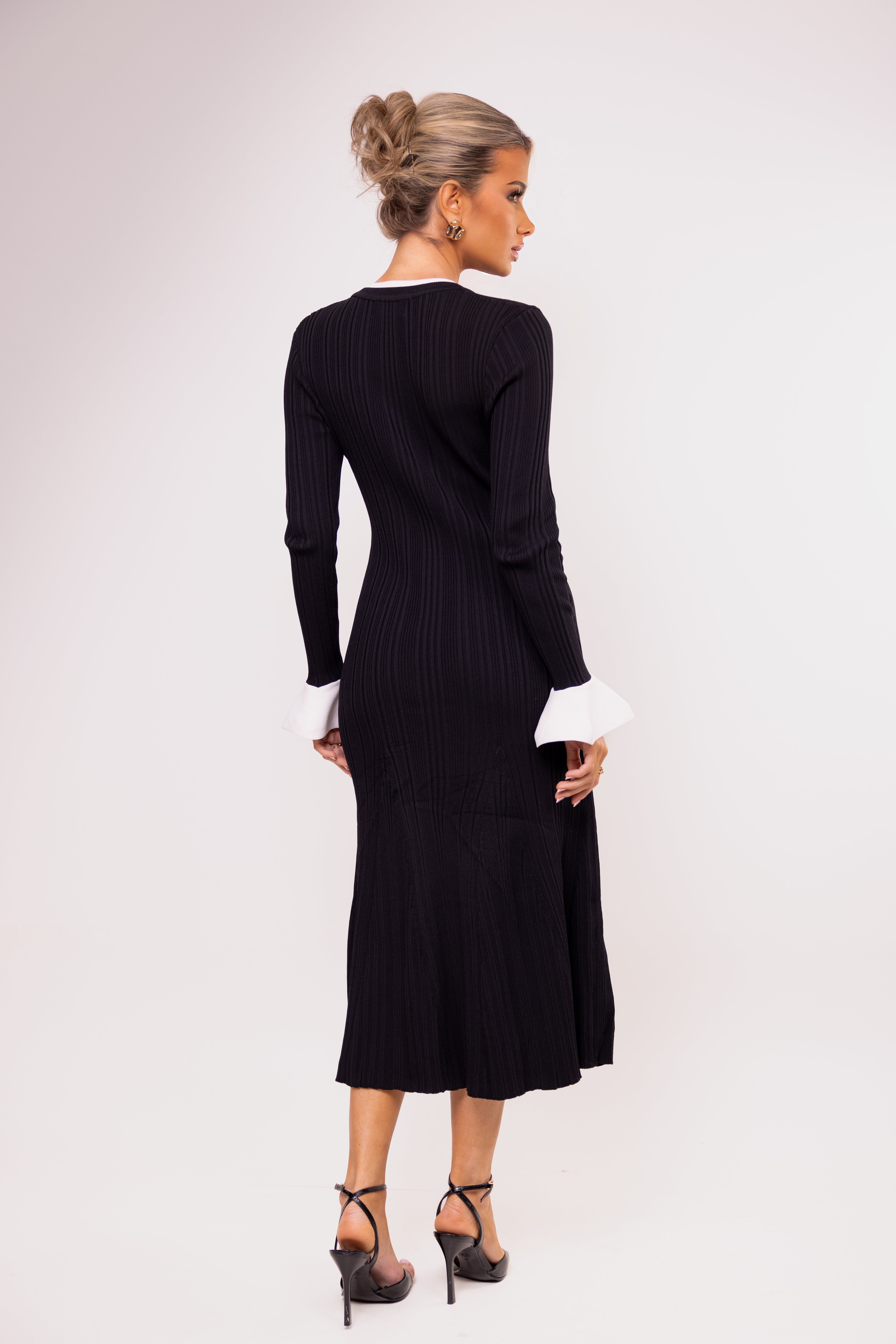 Woman wearing a black ribbed dress with long sleeves on a white background