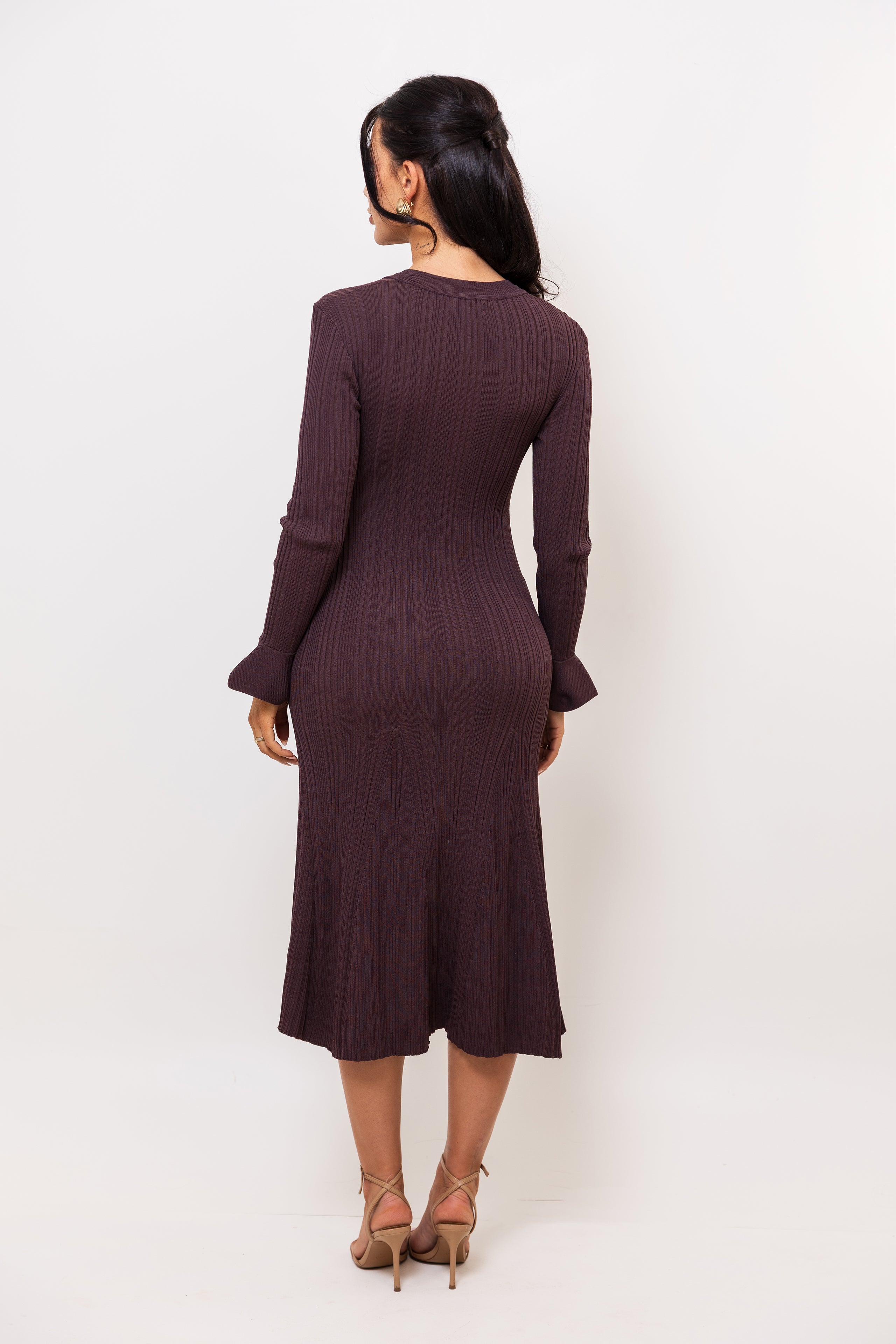 Woman wearing a dark brown ribbed dress on a white background