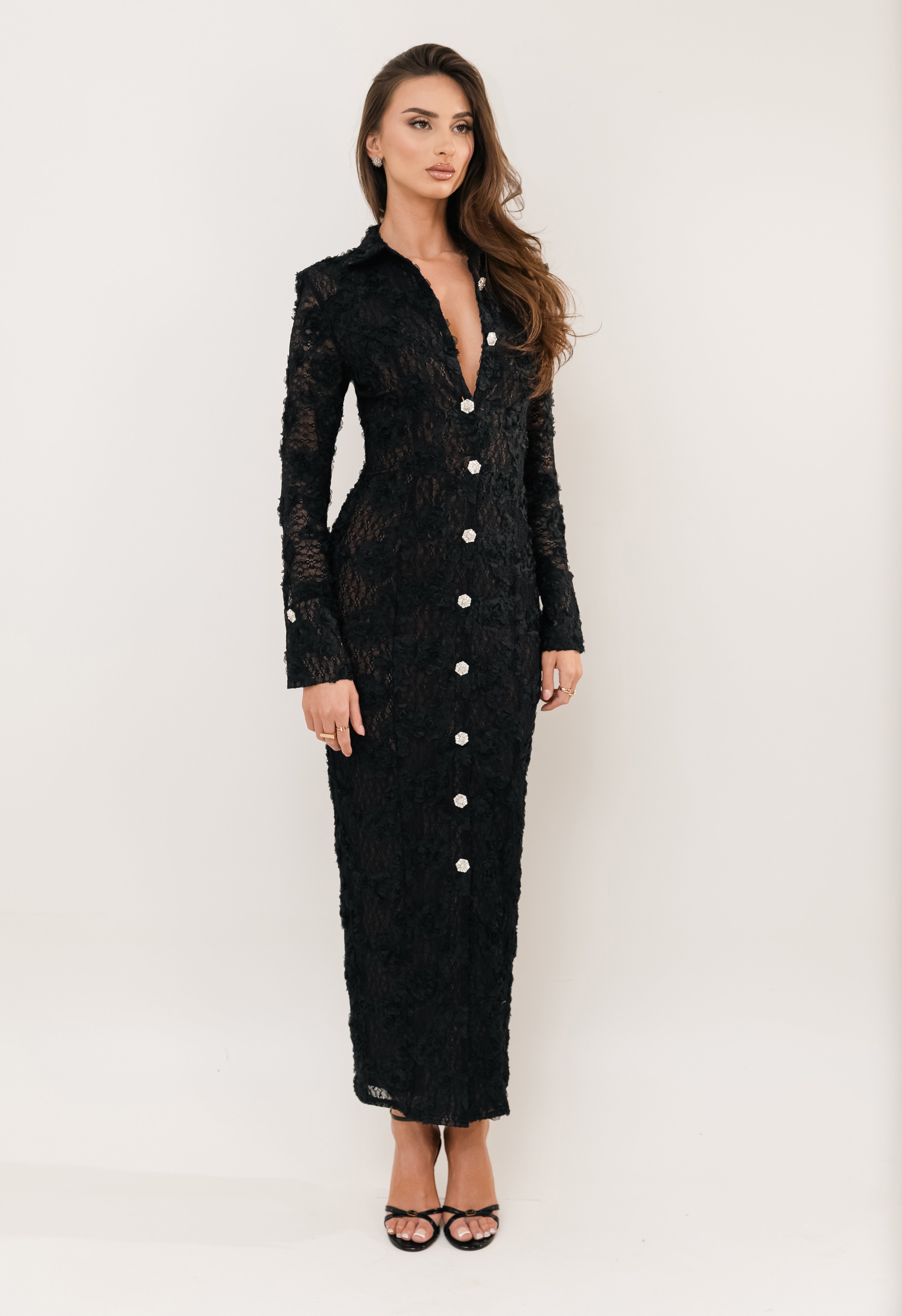 Woman wearing a black lace dress with white buttons on a white background