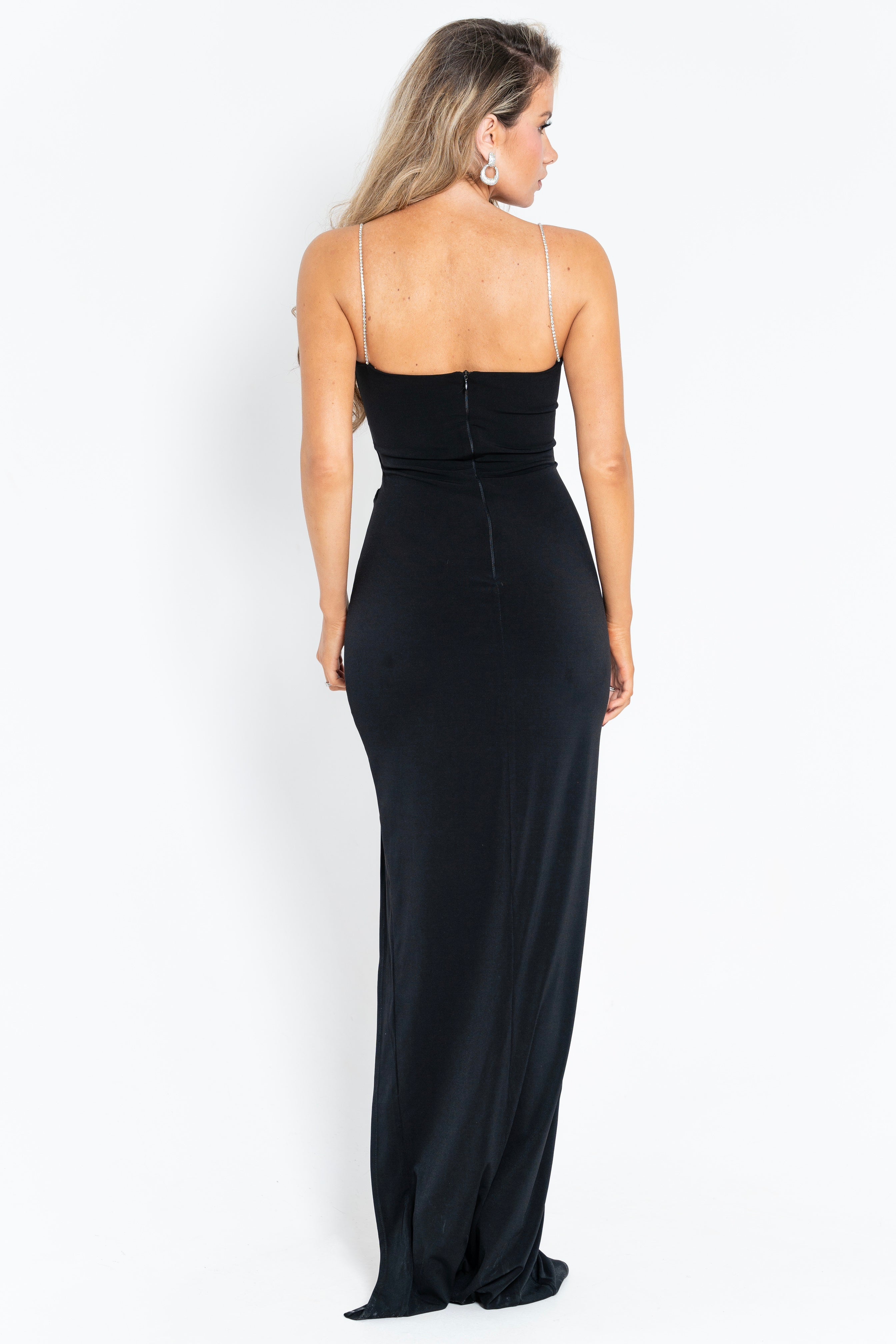 A sleek black maxi dress with a chic floral embellishment on the chest and a side slit for an elegant silhouette.