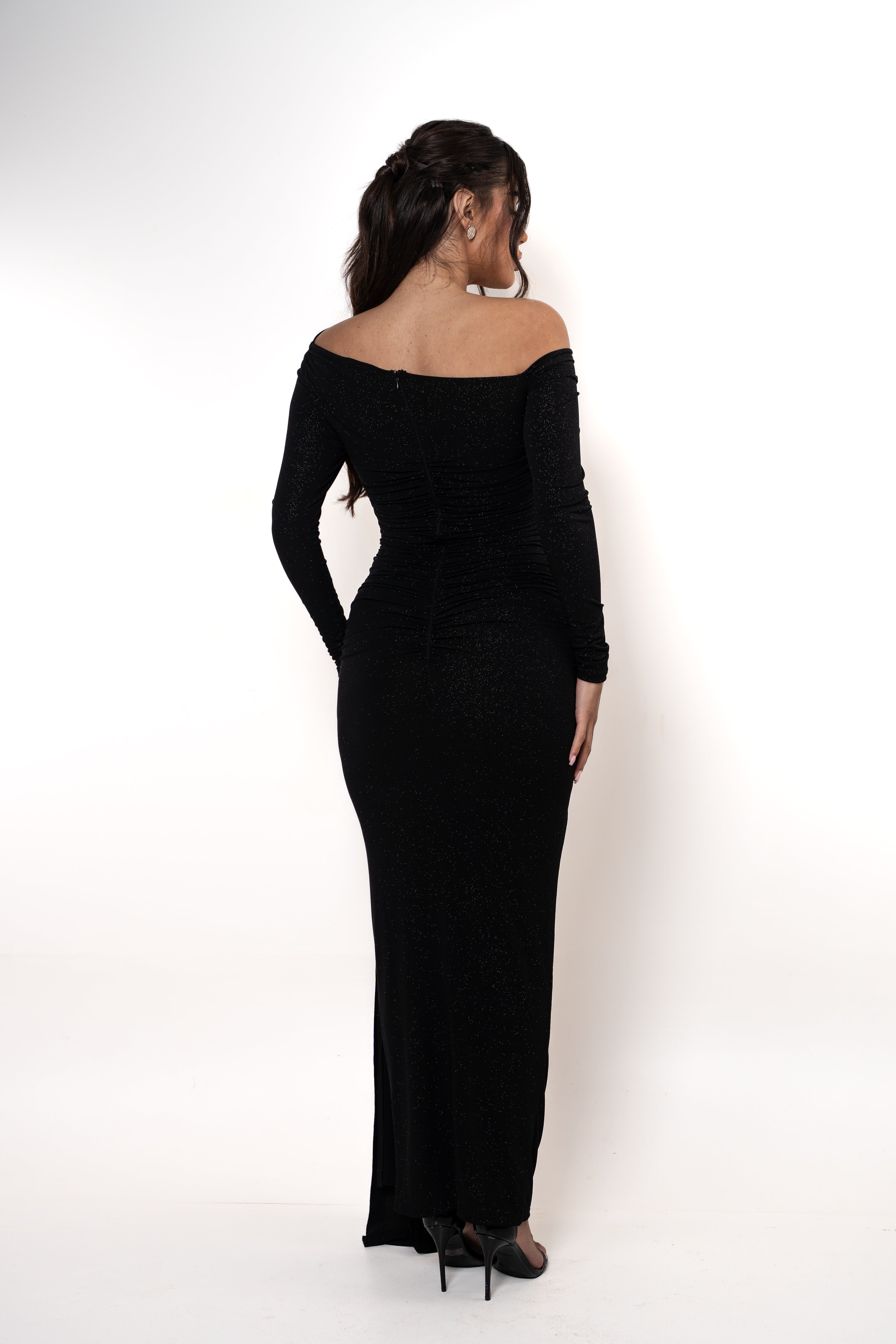 Woman wearing a black off-shoulder dress against a white background