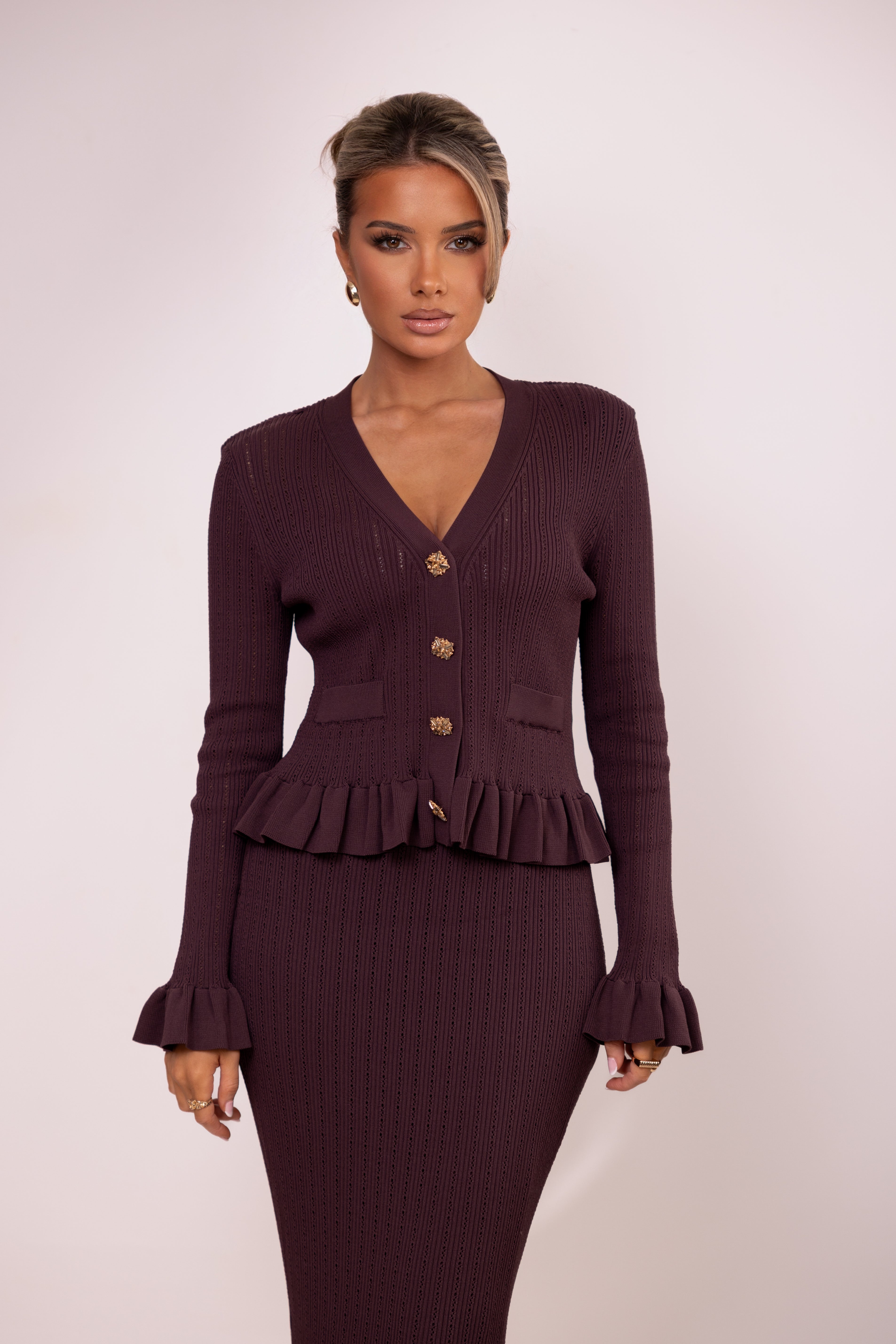 Woman wearing a maroon peplum top and skirt set on a white background