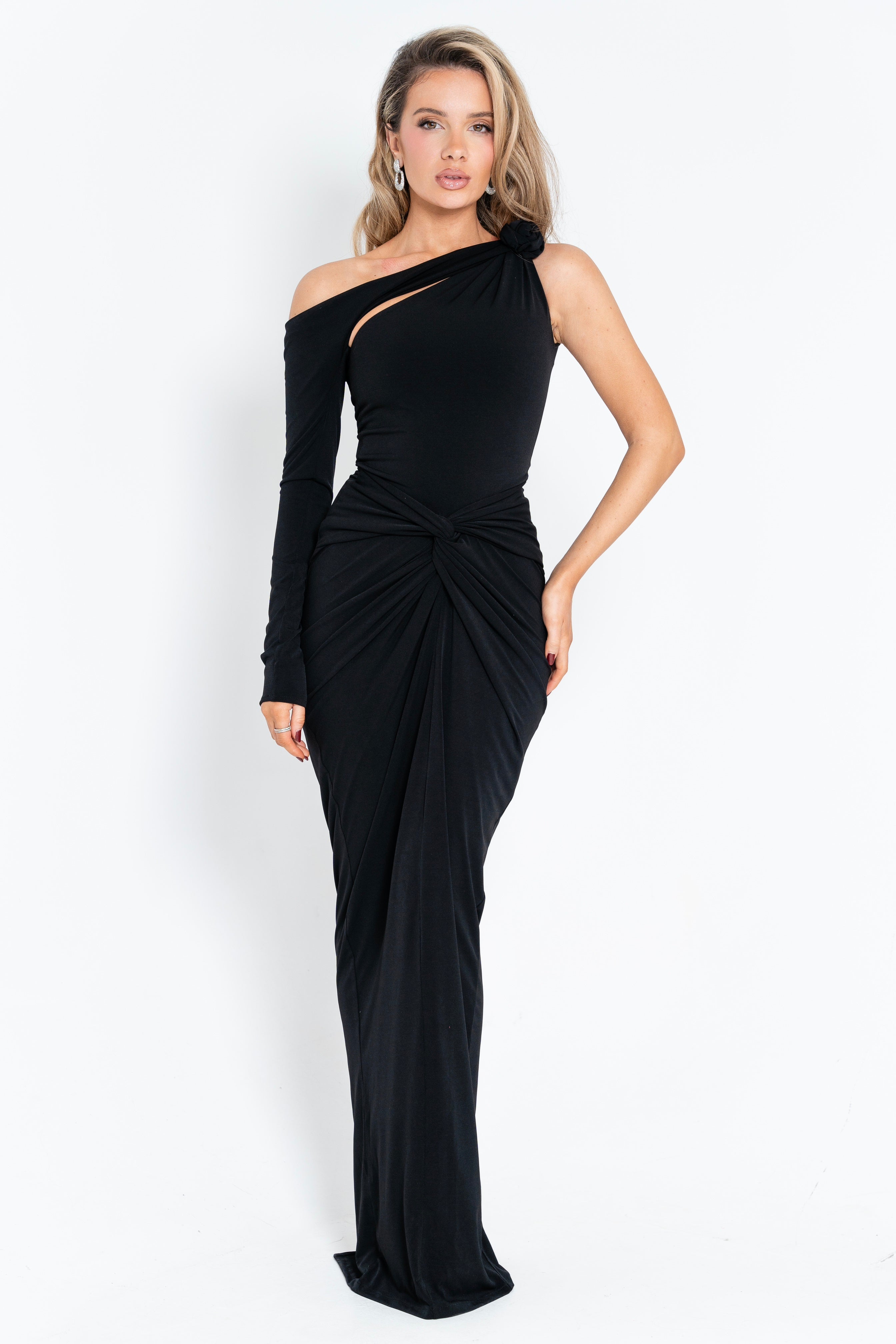 Elegant black dress with a dramatic off-shoulder neckline, knot detail, and flowing floor-length design.