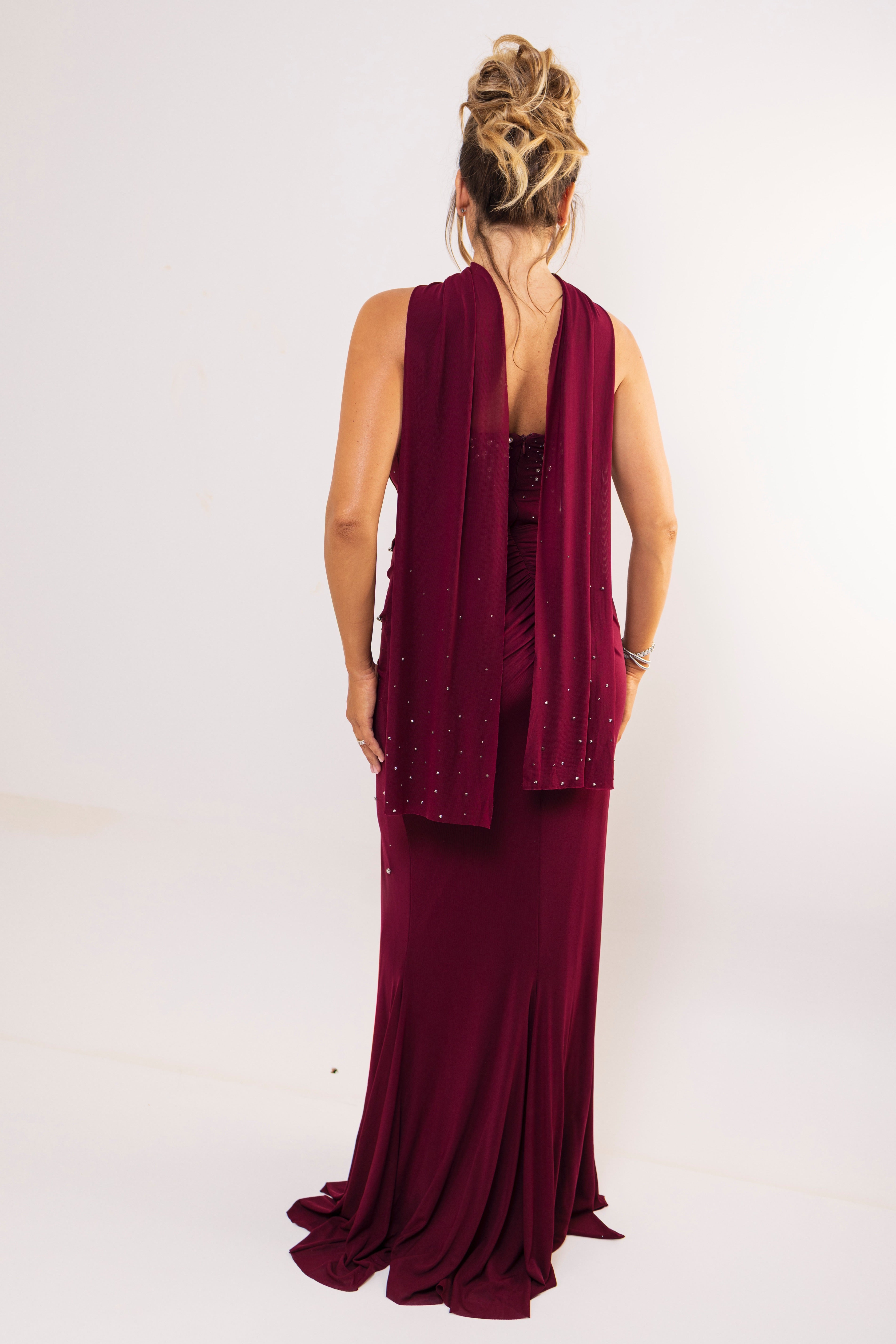 Back view of floor-length burgundy dress with flowing panels.