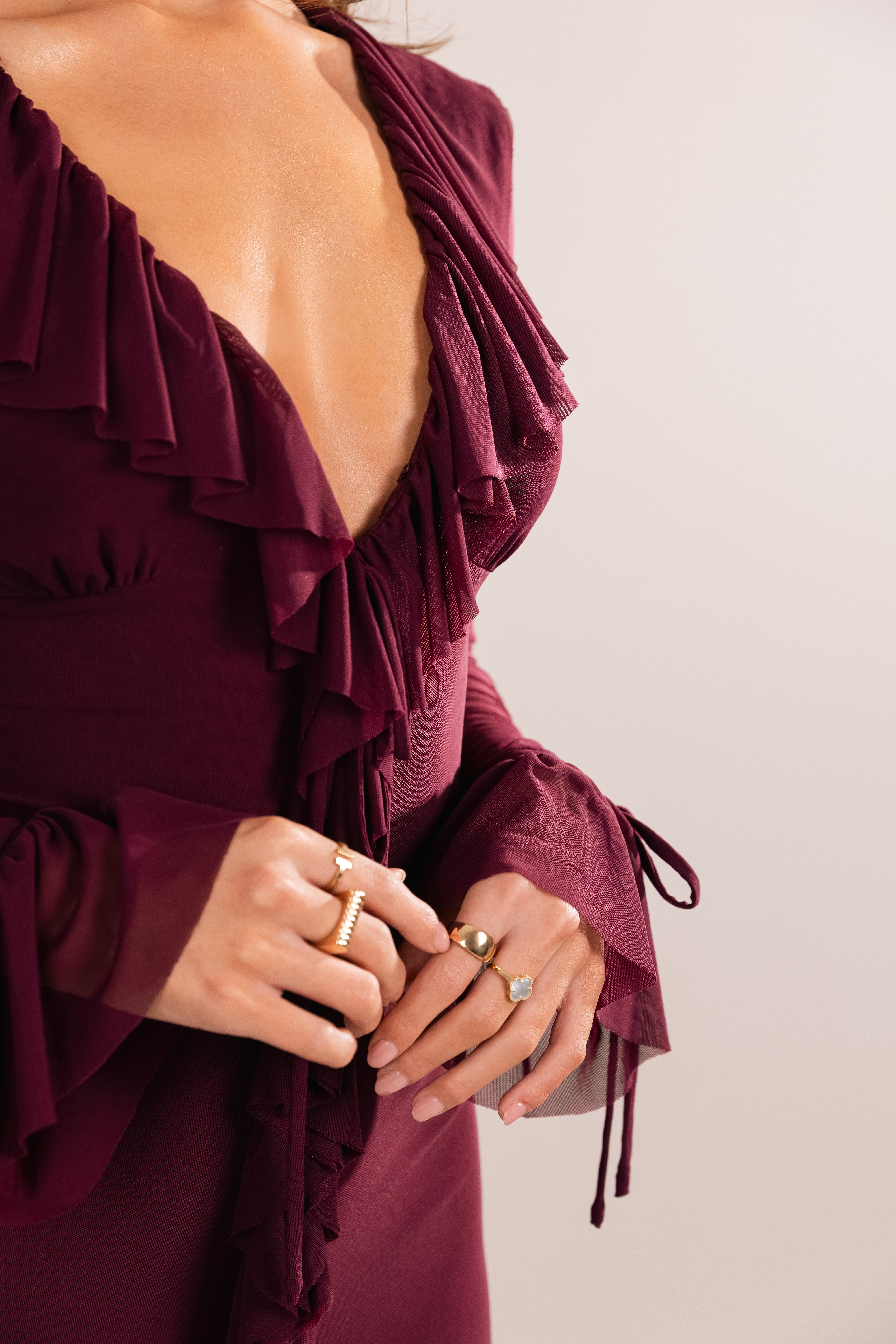 Close-up of a burgundy dress with ruffled details and a plain background