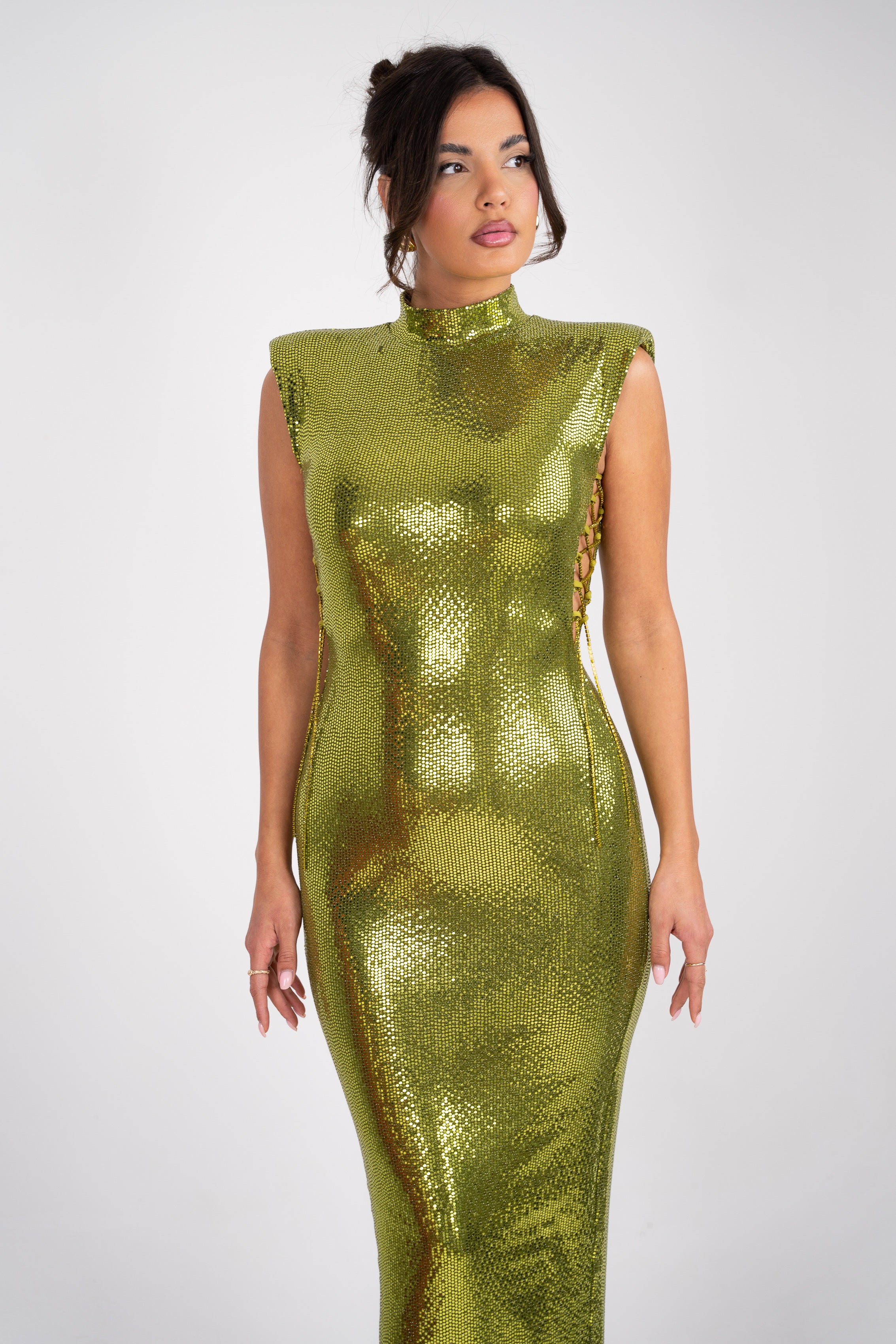 Woman in a sleek, shimmering gold dress with bold shoulders