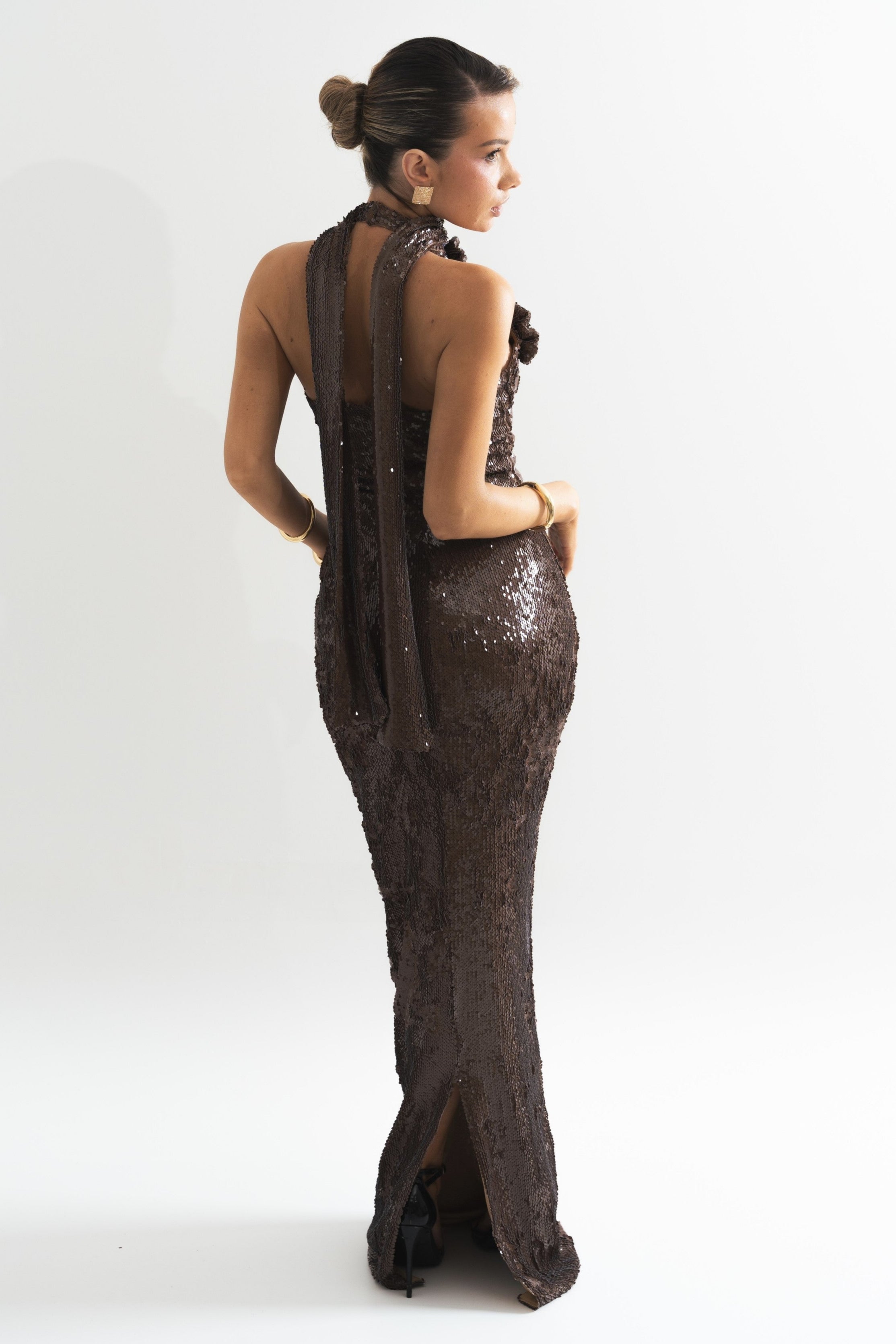 Radiant brown evening gown featuring sparkling sequins, a high neck, and a floral detail for added elegance.