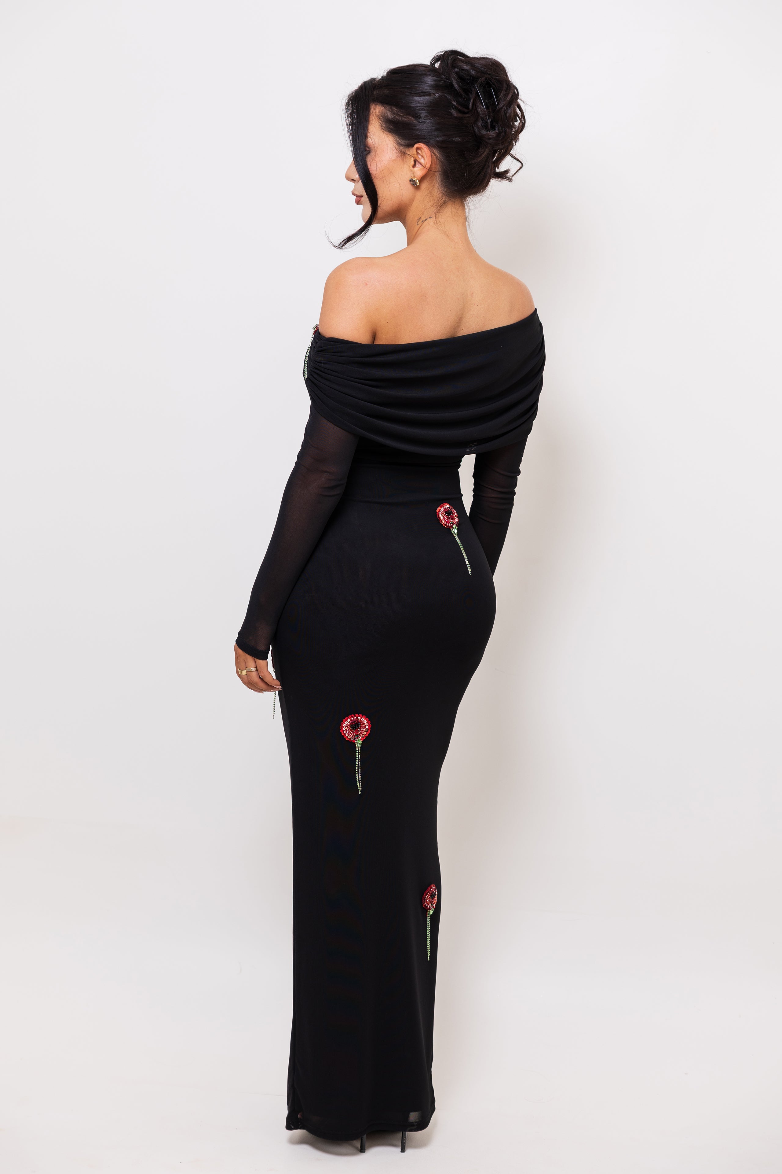 Woman wearing a black off-shoulder dress with red accents on a white background