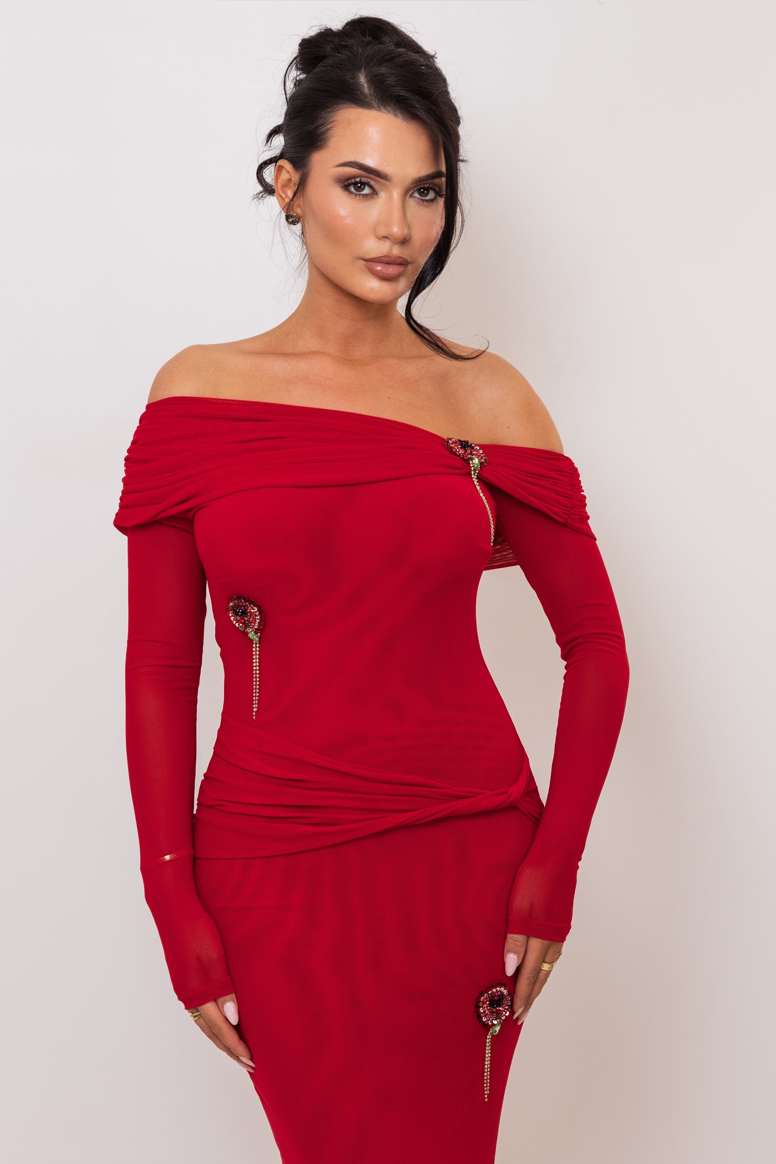 Woman wearing a red off-shoulder dress with gold buttons on a white background