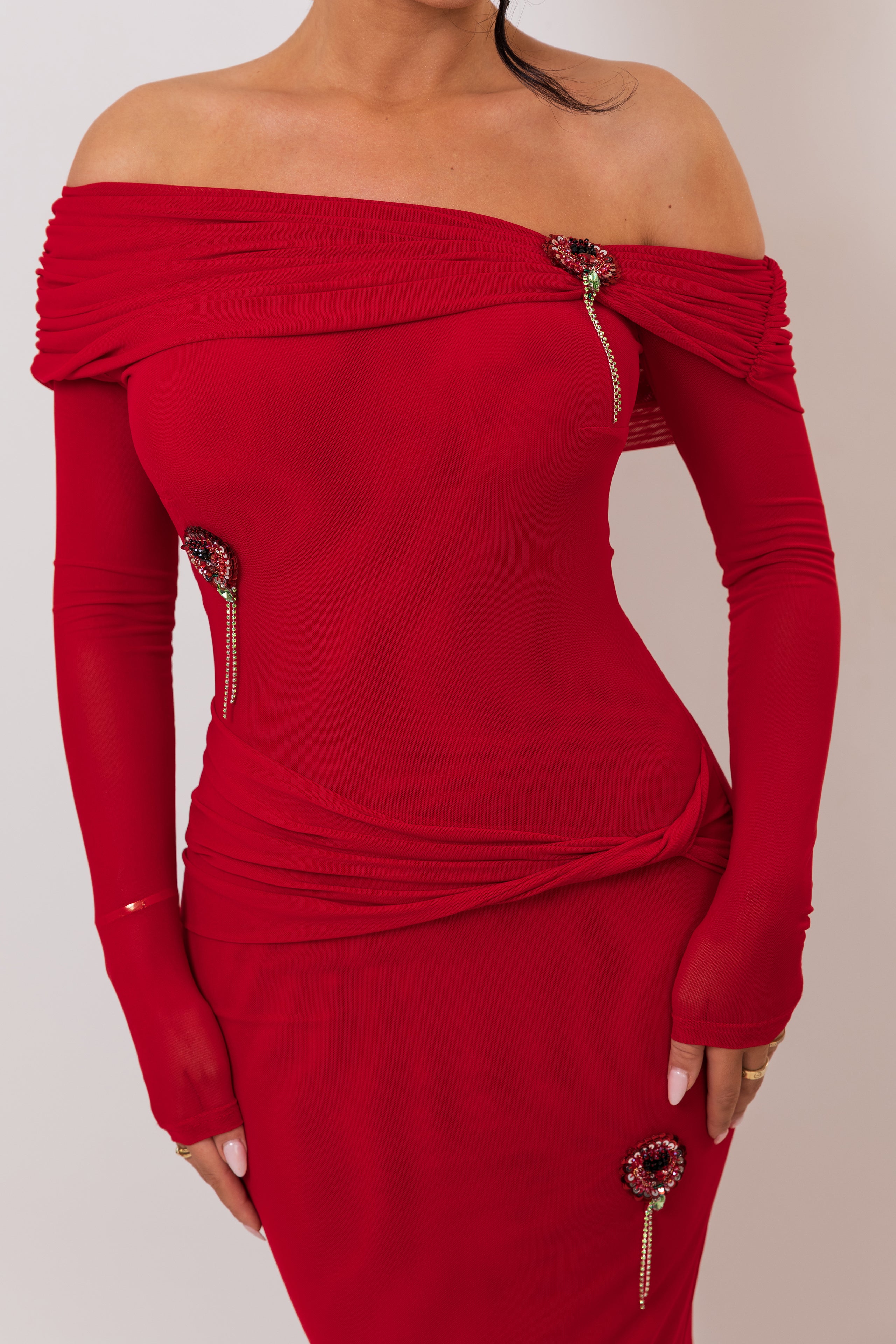 Red off-shoulder dress with embellishments on a plain background