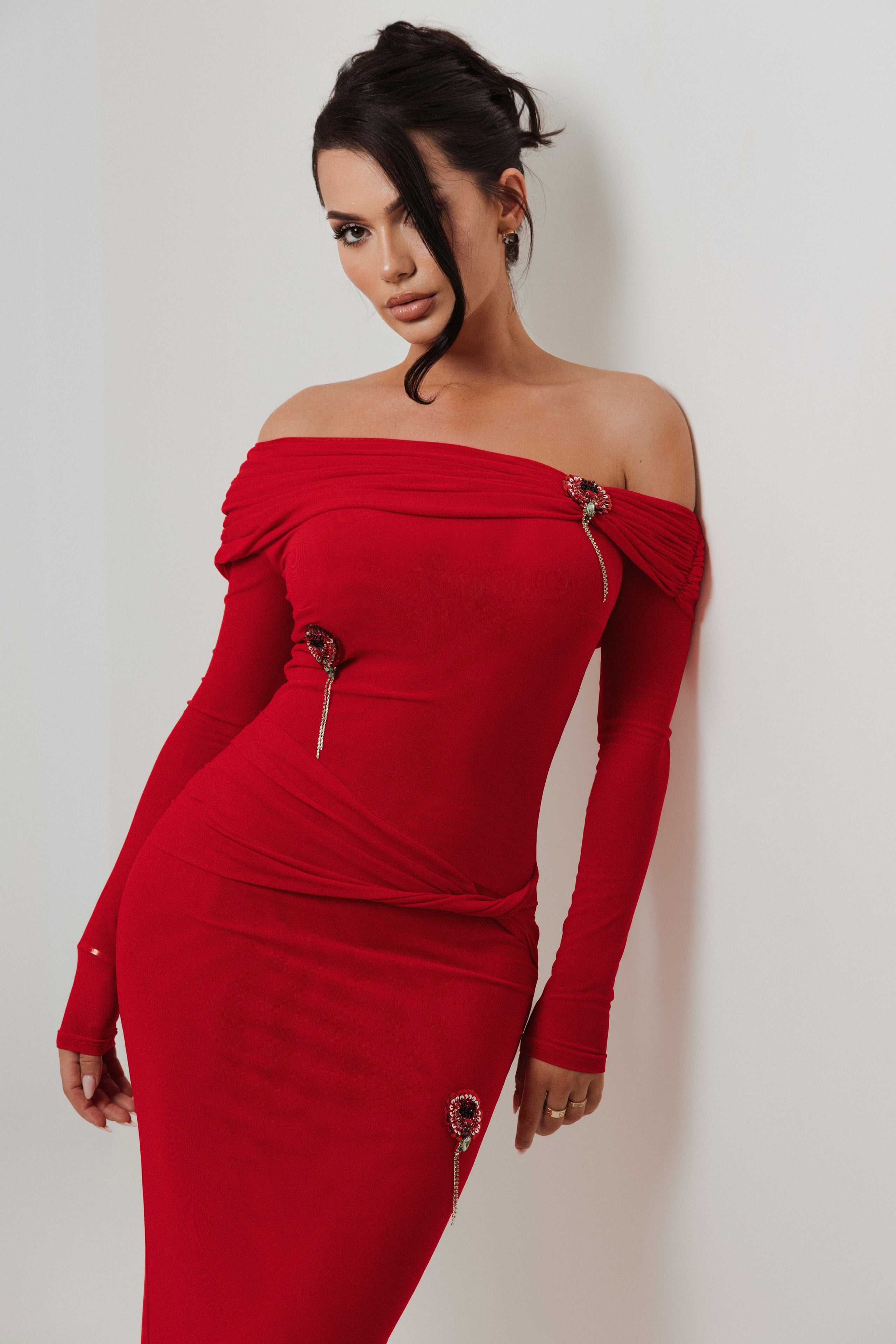 Woman wearing a red off-shoulder dress against a plain background