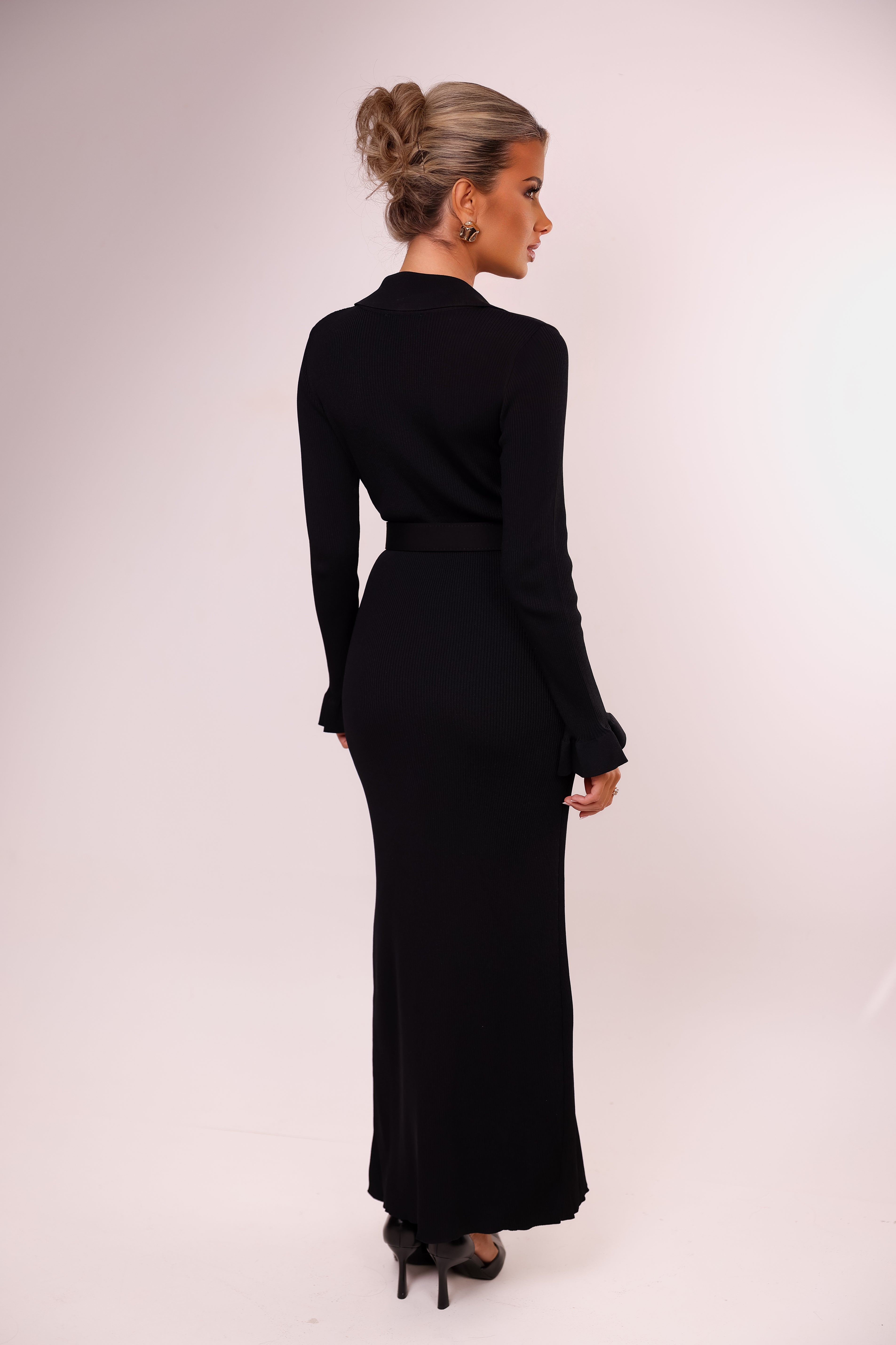 Woman wearing a black long-sleeve dress against a white background