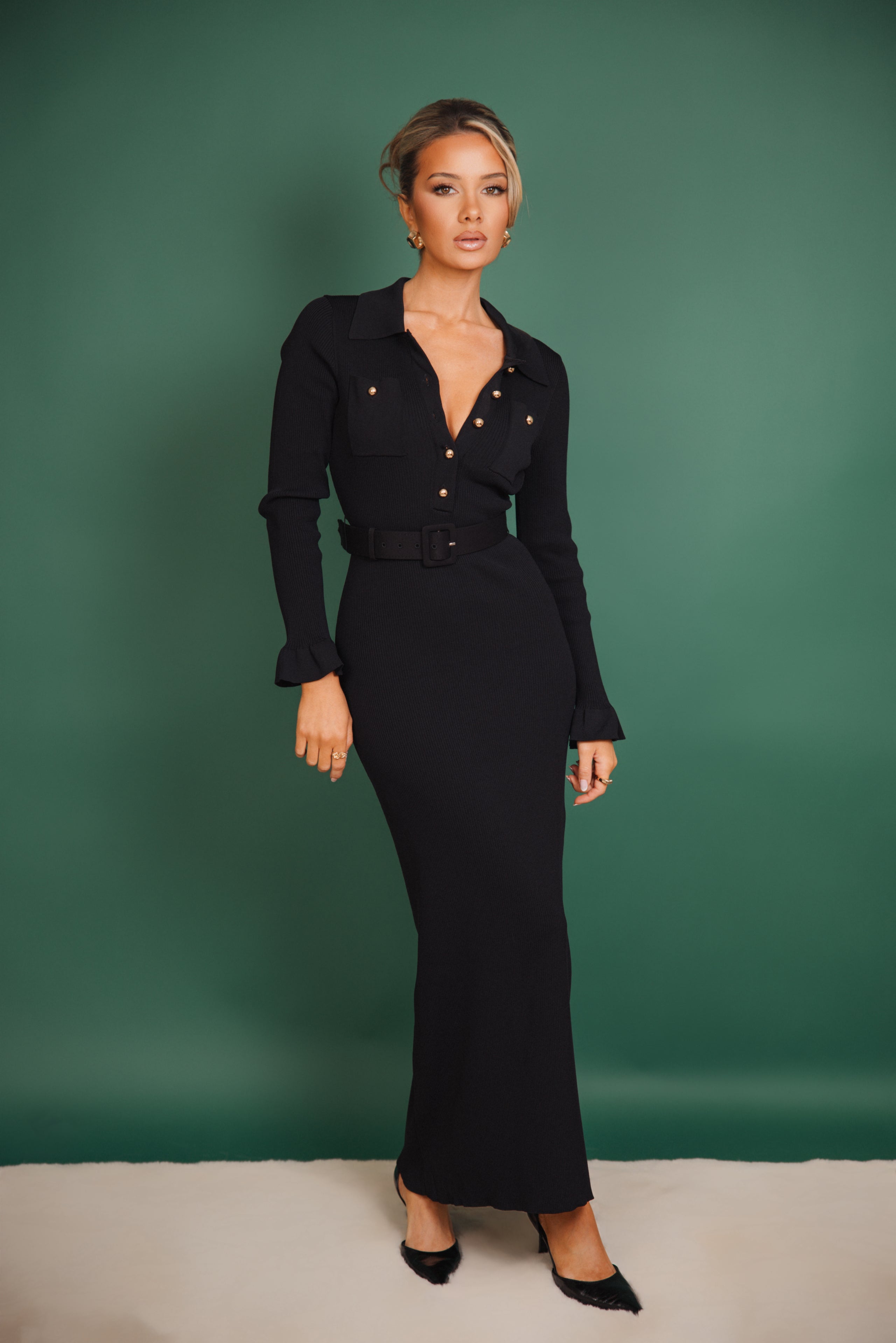 Woman wearing a black dress against a green background