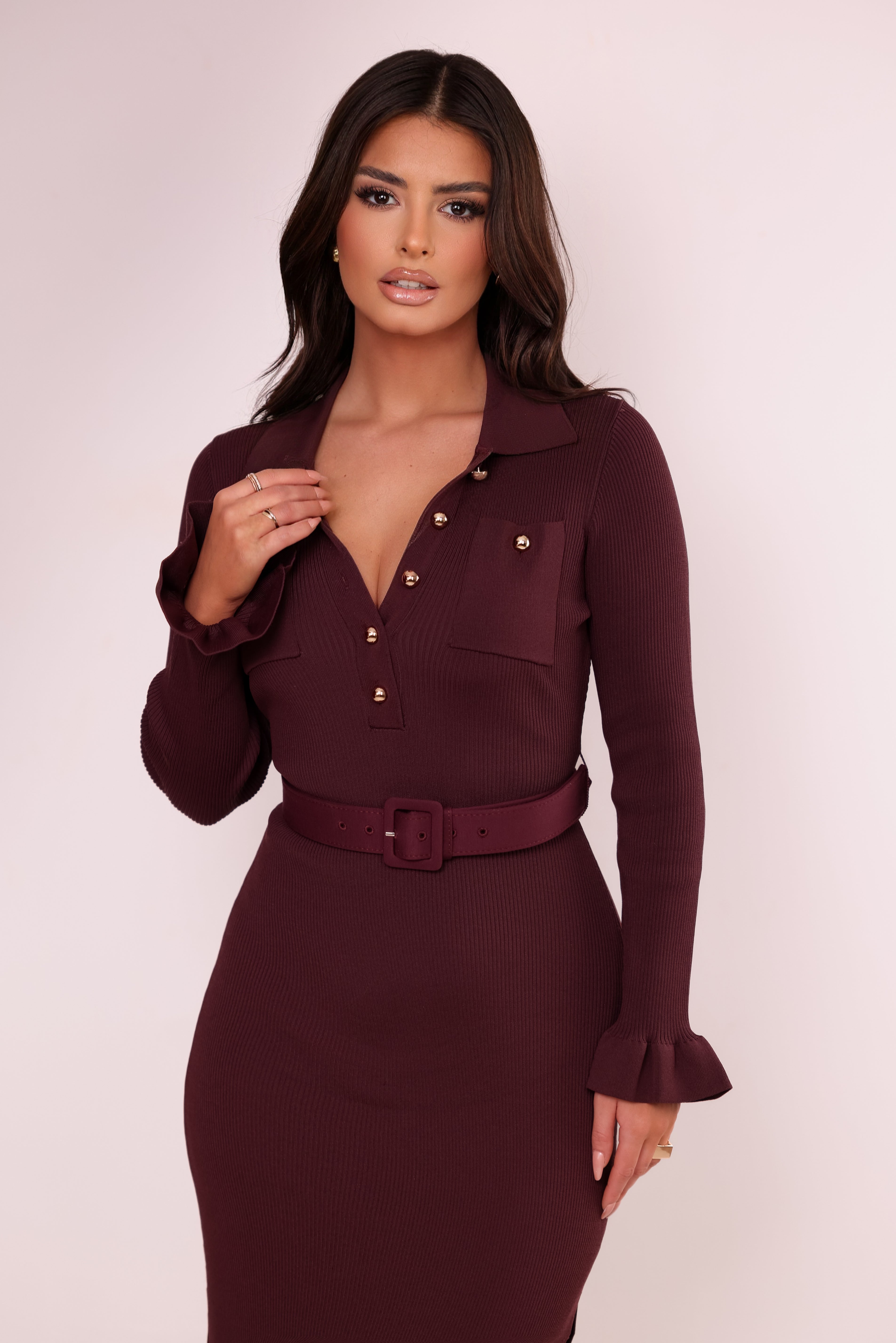 Woman wearing a burgundy dress with a belt against a white background